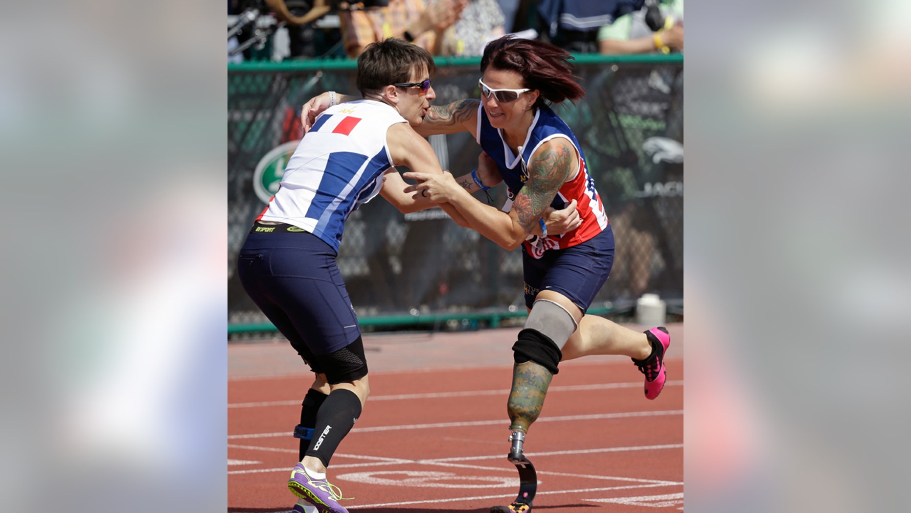 May 10, 2016: Marion Blot, left, of France, the winner of the women's 200 meter IT1 race, catches Sarah Rudder of the United States as she stumbles across the finish line at the Invictus Games in Kissimmee, Fla.