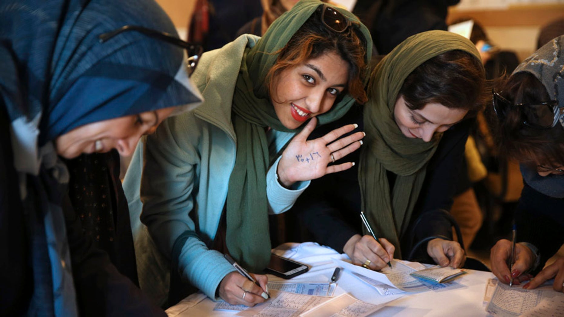 Feb. 26, 2016: An Iranian voter shows her hand with numbers 30+16, a reformists slogan urging people to vote all reformists and moderate candidates in Tehran for both parliament and Assembly of Experts during the elections, as she fills out her ballot in a polling station in Tehran, Iran.