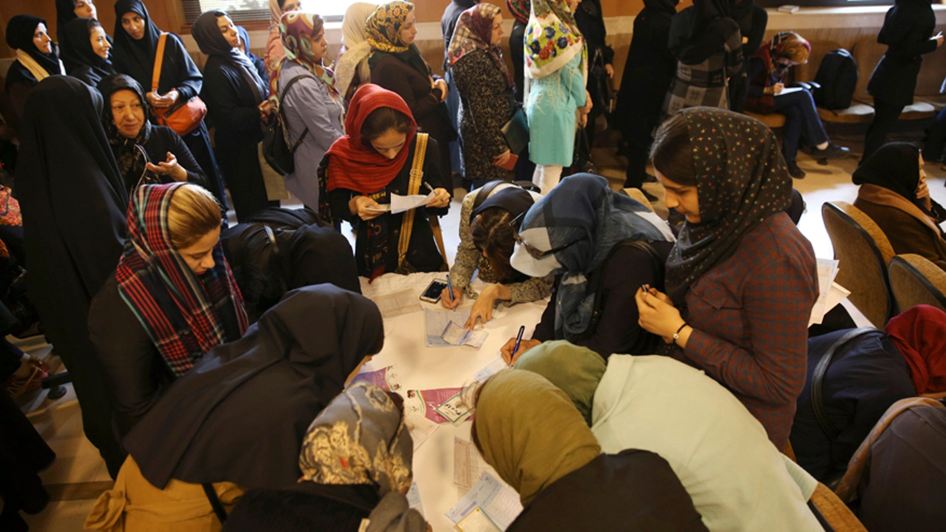Feb. 26, 2016: A group of Iranian voters fill out their ballots as the others queue for getting ballot papers during the parliamentary and Experts Assembly elections in a polling station in central Tehran, Iran.