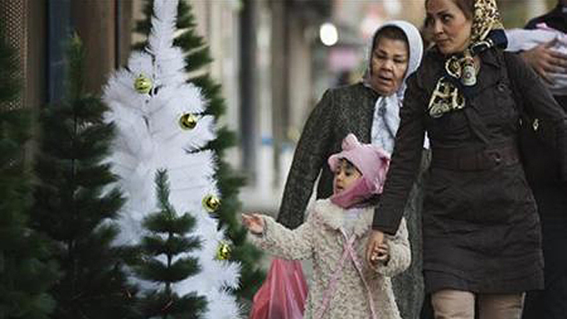 Girl looks at Christmas tree as she and her mother walk past Christmas decorations in central Tehran. (Reuters)