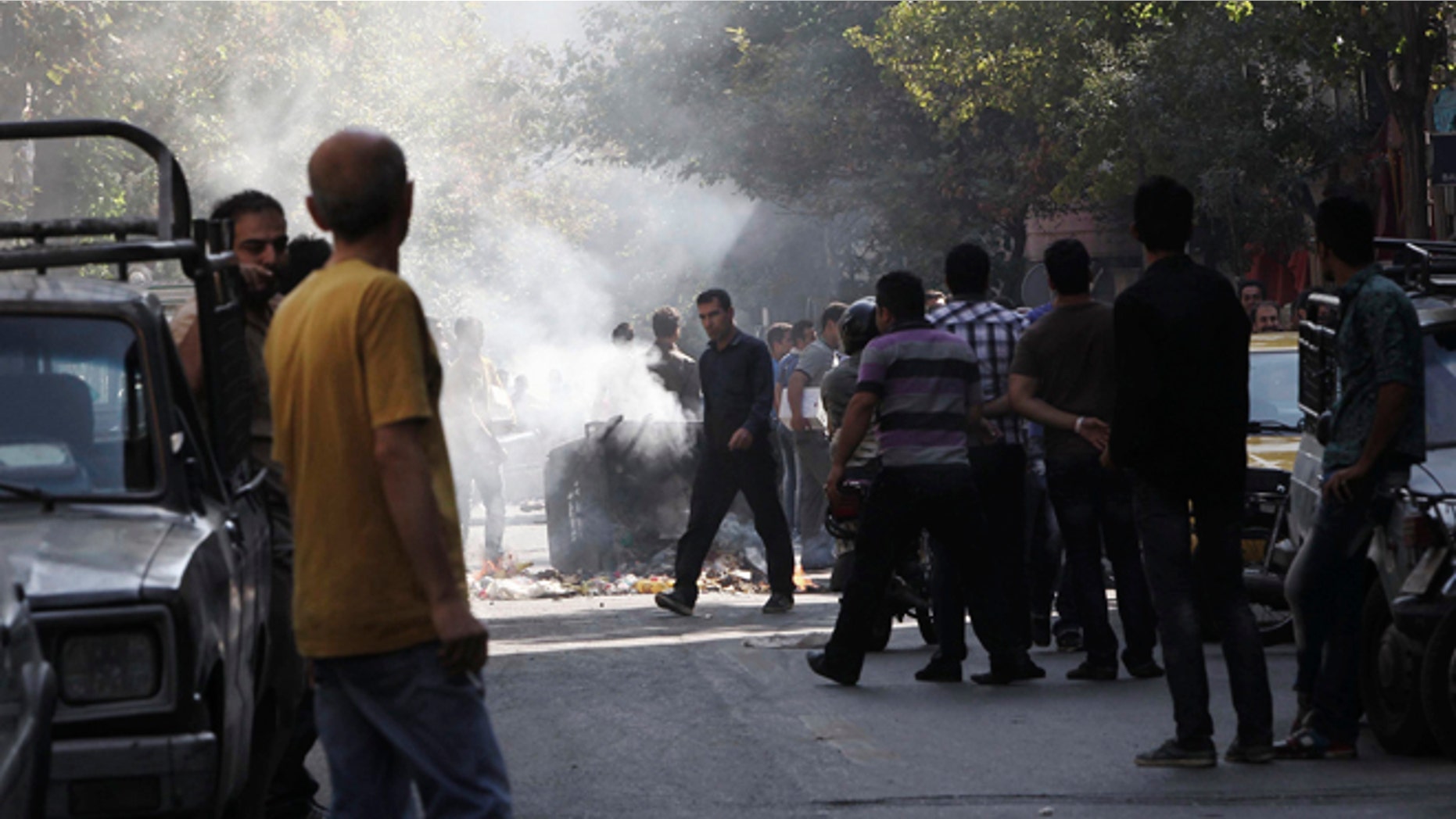 Oct. 3, 2012: This photo, taken by an individual not employed by the Associated Press and obtained by the AP outside Iran shows, Iranians stand in a street as a garbage can is set on fire, in central Tehran, near Tehran's old main bazaar.