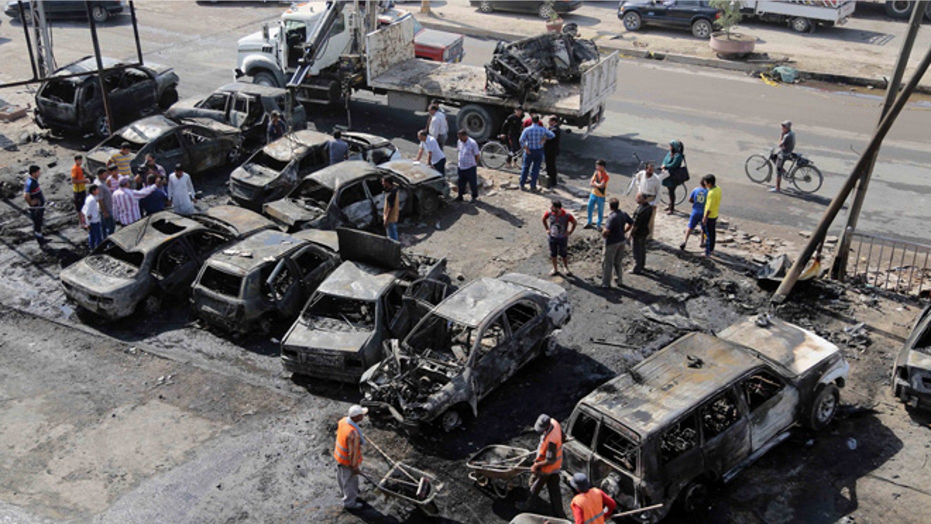 Oct. 27, 2013: Baghdad municipality workers clear debris while citizens inspect the site of a car bomb attack in the Shaab neighborhood of Baghdad, Iraq. Insurgents on Sunday unleashed a new wave of car bombs in Shiite neighborhoods of Baghdad, killing and wounding some dozens of people, officials said