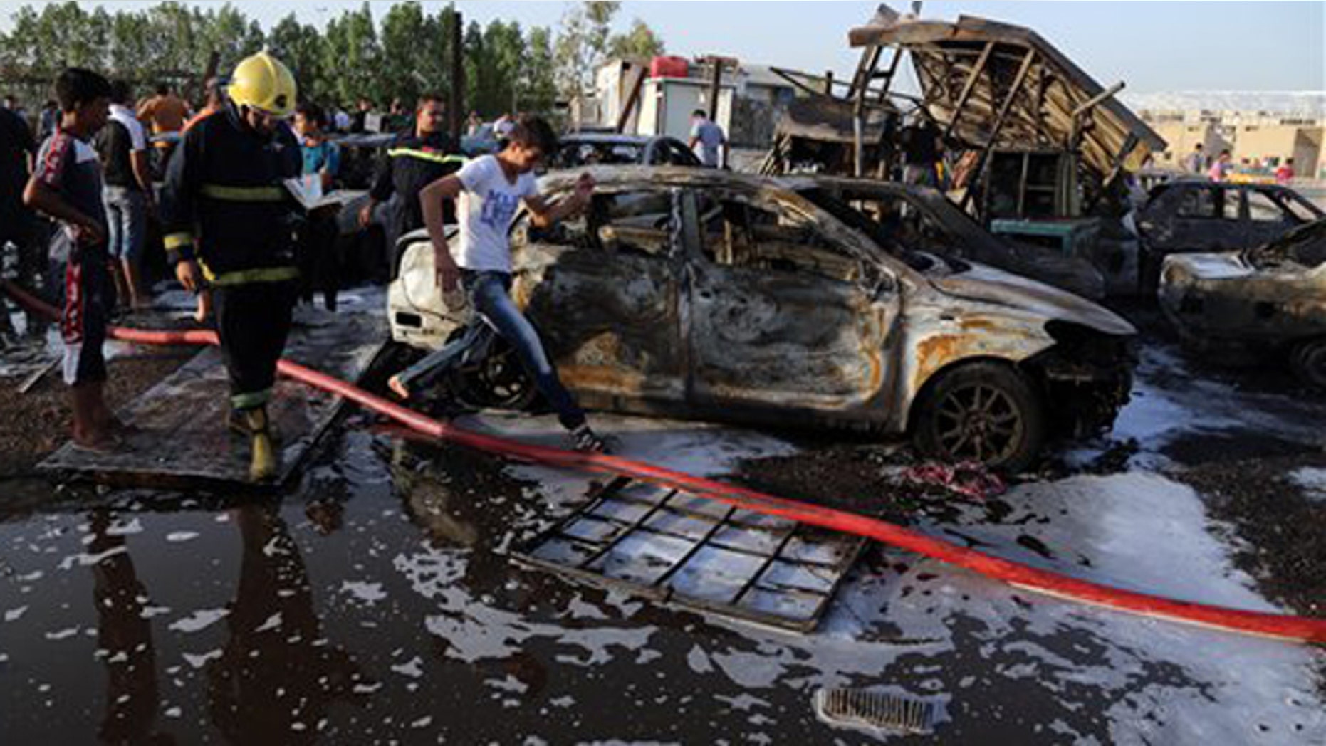Aug 15, 2015: Civilians and security forces gather at the scene of a deadly car bomb in the Habibiya neighborhood of Sadr City, Baghdad, Iraq.