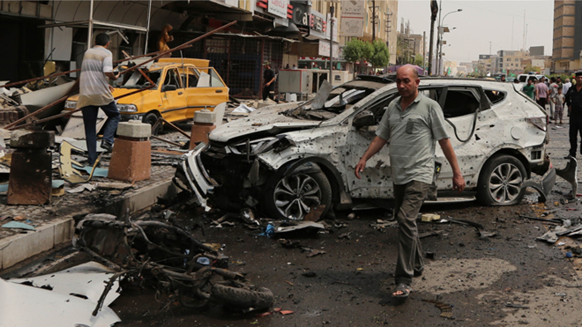 May 9, 2015: Civilians and security forces inspect the scene of a car bomb explosion in Karrada neighborhood, Baghdad, Iraq. (AP)