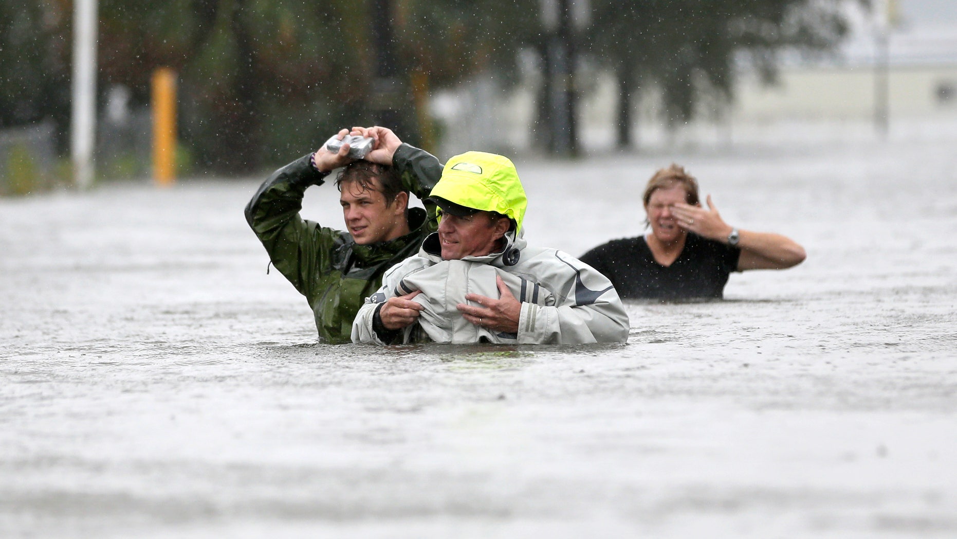 Chuck Cropp, center, his son Piers, left, and wife Liz, right, wade through floodwaters from Hurricane Isaac Wednesday, Aug. 29, 2012, in New Orleans. As Isaac made landfall, it was expected to dump as much as 20 inches of rain in several parts of Louisiana. (AP Photo/David J. Phillip)