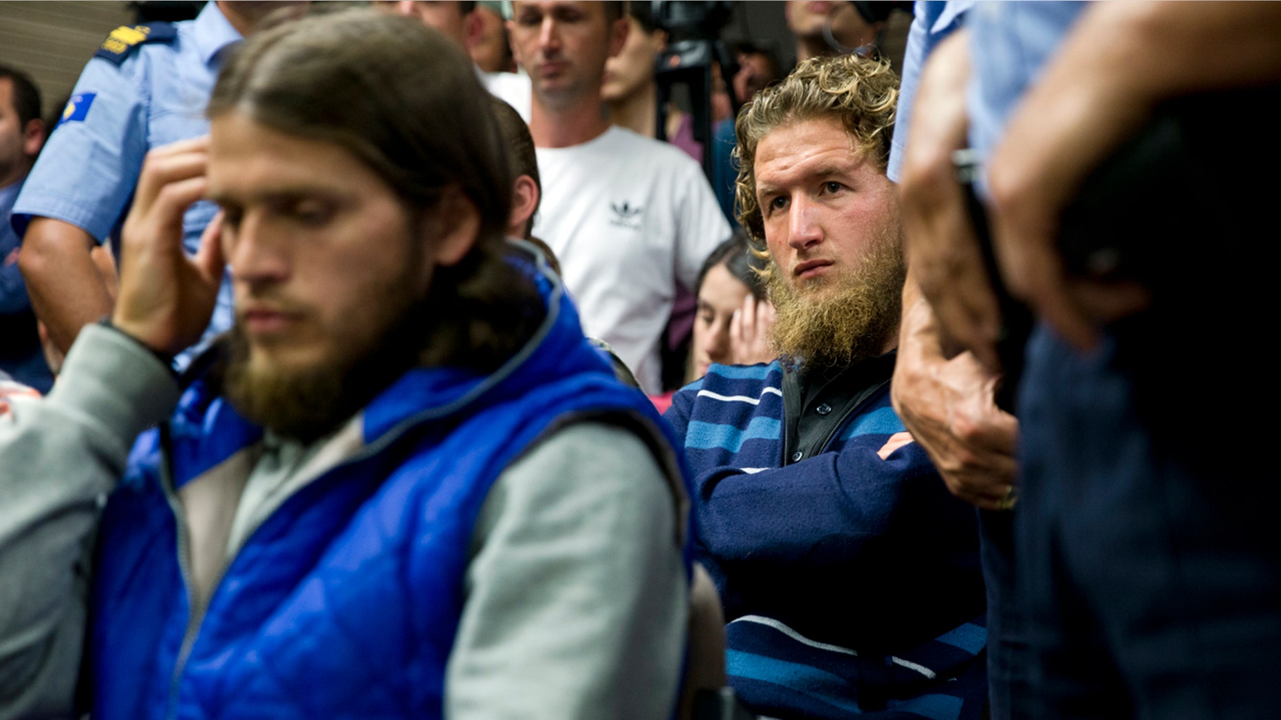 Kosovo police officers stand guard by Arton Ahmeti, left, Leotrim Musliu, right, in court for the foiled attack against the Israeli team in a 2016 qualifying World Cup match in neighboring Albania, in Kosovo's capital Pristina on Friday, May 18, 2018. A Kosovo court has sentenced nine Albanians from a fine to 10 years of jail for planning an attack against the Israeli team in a 2016 qualifying World Cup match. The group, also with members in Albania and Macedonia, was coordinated by two Albanians part of the IS terror group in Syria to hold the attack in November 2016. Police found explosive devices, weapons, electronic equipment and extremist religious literature at their homes. (AP Photo/Visar Kryeziu)