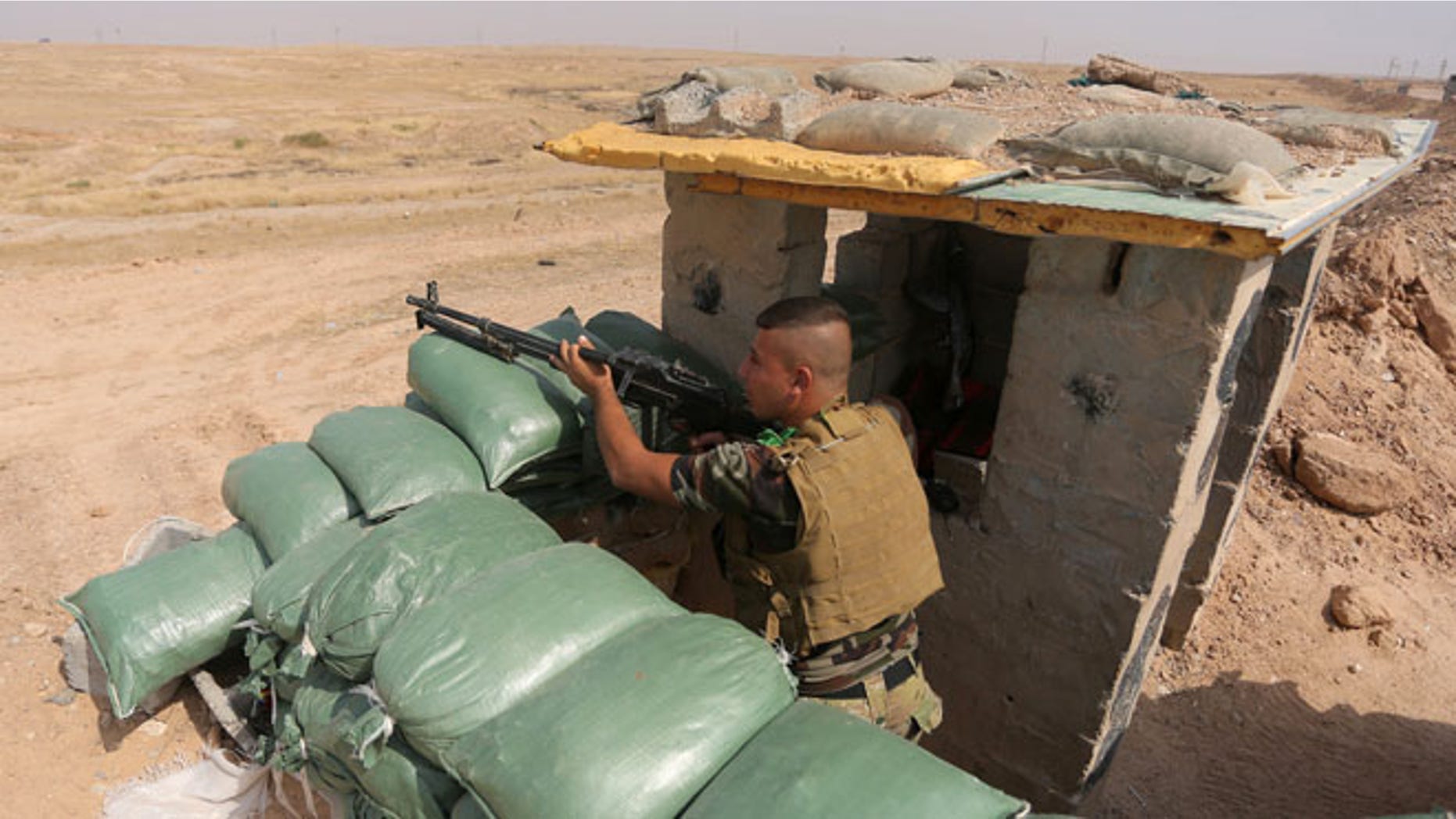 Oct. 2, 2014: An Iraqi Shiite militiamen takes cover after clashes with militants from the Islamic State group