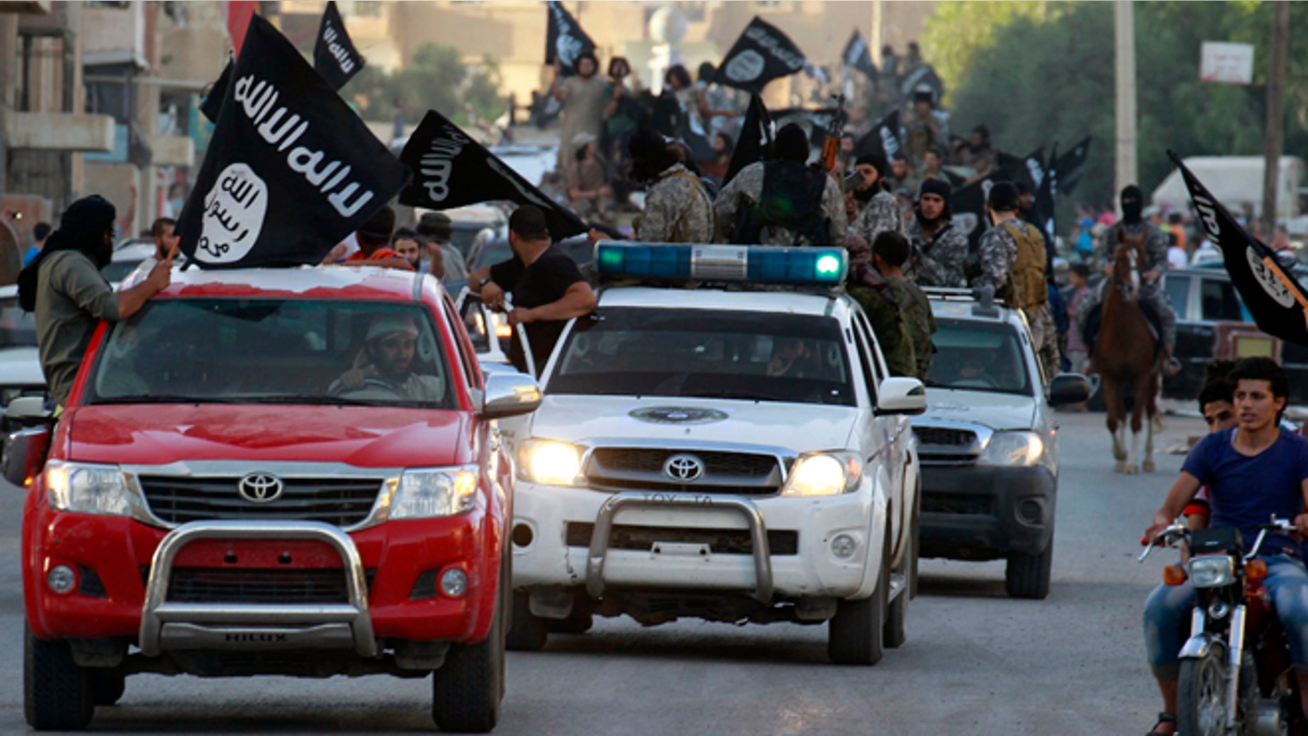 June 30, 2014: Militant Islamist fighters waving flags, travel in vehicles as they take part in a military parade along the streets of Syria's northern Raqqa province. The fighters held the parade to celebrate their declaration of an Islamic "caliphate" after the group captured territory in nearby Iraq, a monitoring service said.
