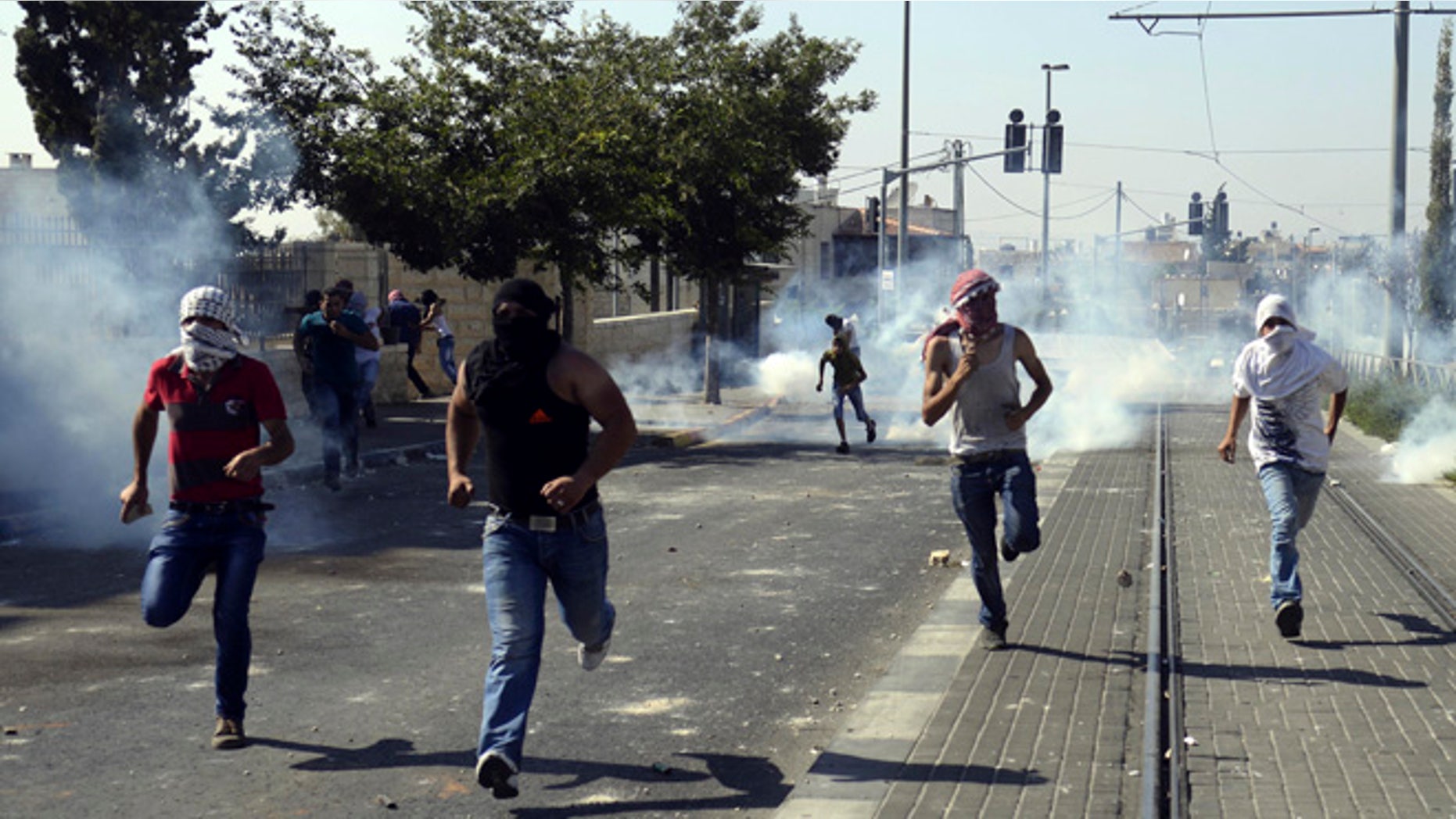 July 4, 2014: Palestinians run away from tear gas as they clash with Israeli security forces during the funeral of 16-year-old Mohammed Abu Khdeir in Jerusalem.