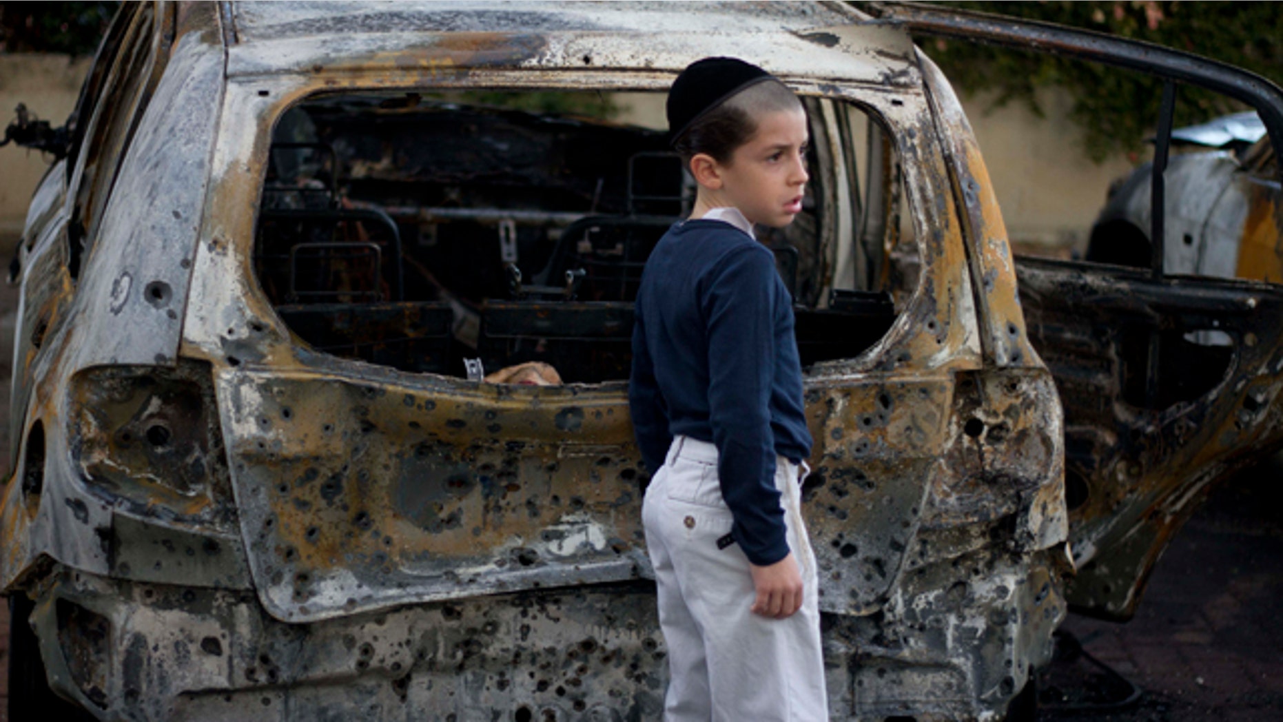 Oct. 30, 2011: A boy stands next to a burned cars following Saturday night's rocket attacks from the Gaza Strip, in Ashdod, southern Israel.