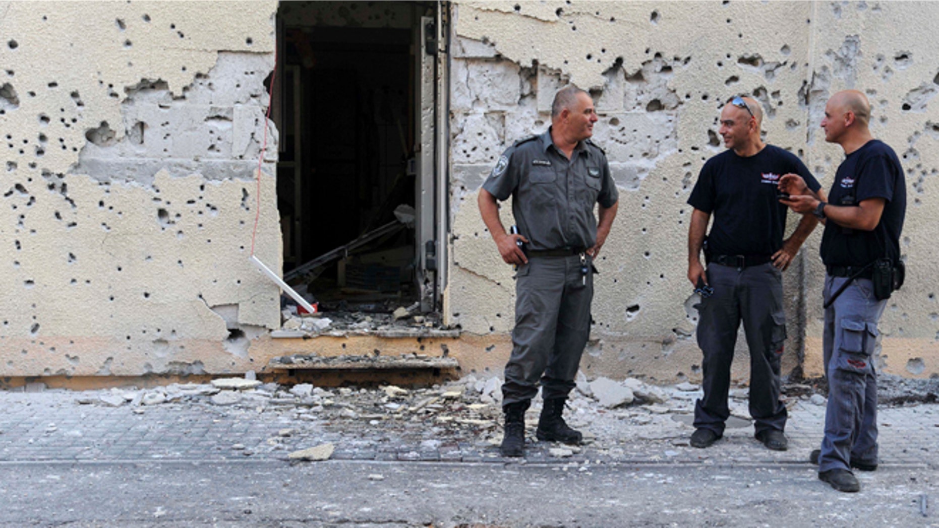 Aug. 22, 2013: Israeli policemen stand in front of a house damaged by a rocket fired from Lebanon in Shavei Tzion outside Nahariya in northern Israel. Military spokesman Lt. Col. Peter Lerner said Thursday that three rockets landed in northern Israel, while one was shot down.