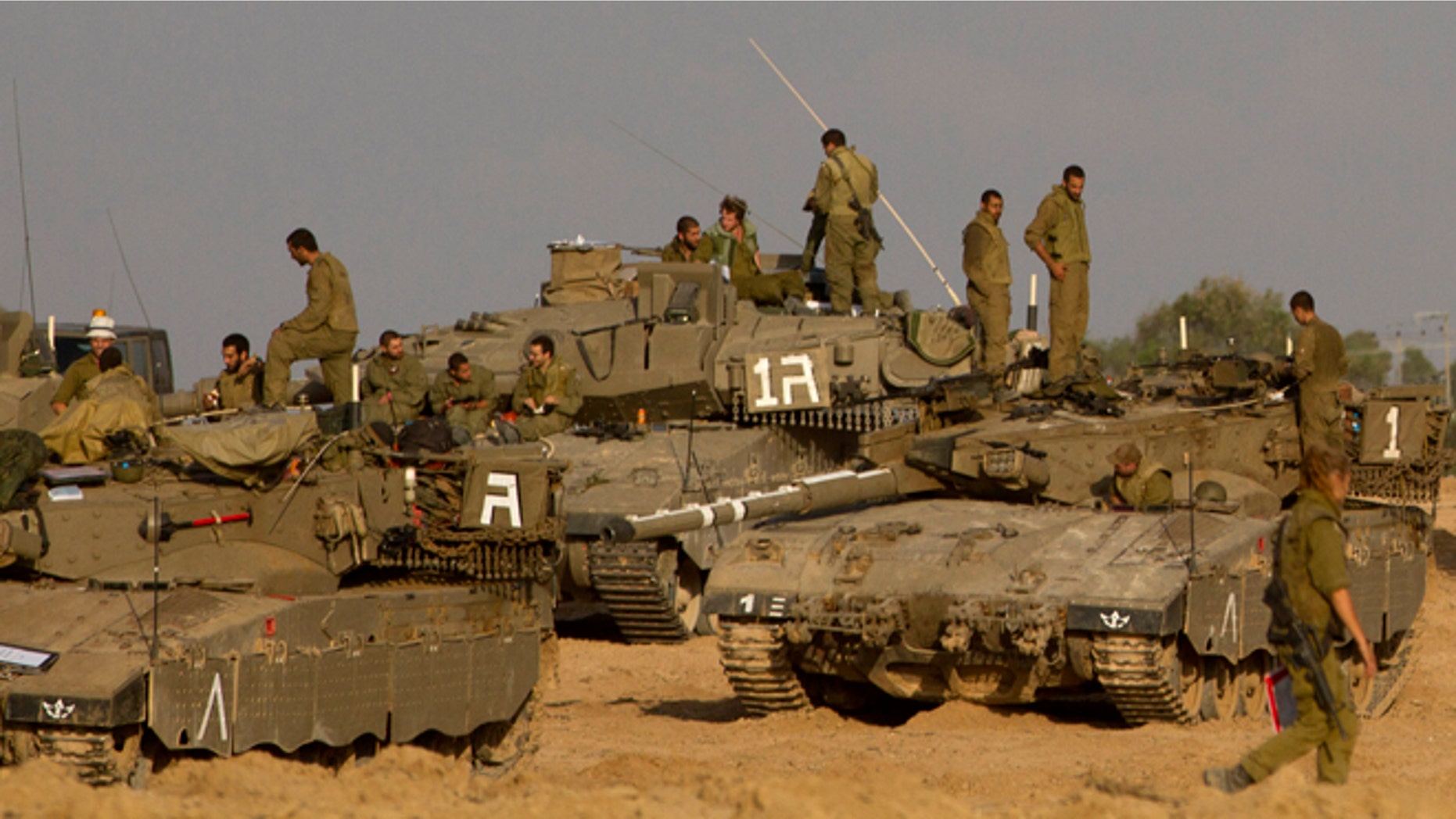 Nov. 18, 2012: Israeli soldiers gather with their tanks and bulldozers in a gathering area near the Israel Gaza Strip border, in southern Israel. President Barack Obama on Sunday defended Israel's airstrikes on the Gaza Strip, but he warned that escalating the offensive with Israeli ground troops could deepen the death toll and undermine any hope of a peace process with the Palestinians.