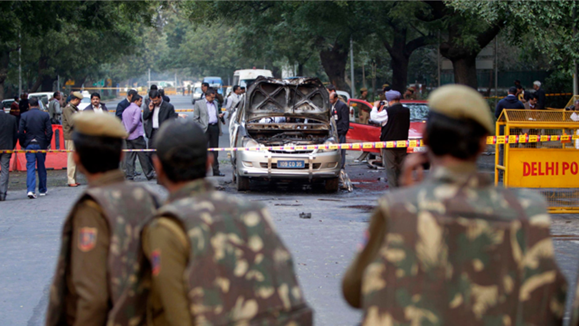 Feb. 13, 2012: Indian policemen watch security and forensic officials examine a car belonging to the Israel Embassy after an explosion tore through that in New Delhi, India.