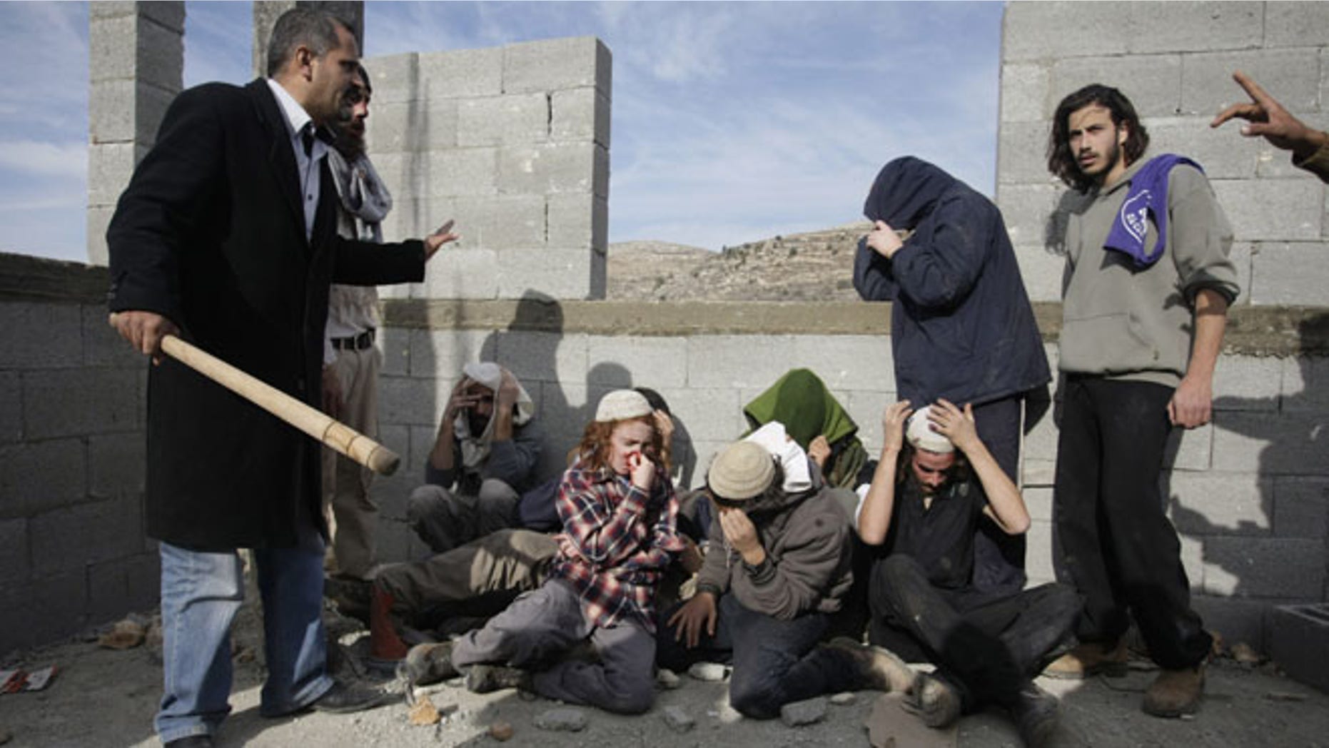 Tuesday, Jan. 7, 2014, Injured Israeli settlers are detained by Palestinian villagers in a building under construction near the West Bank village of Qusra, southeast of Nablus.