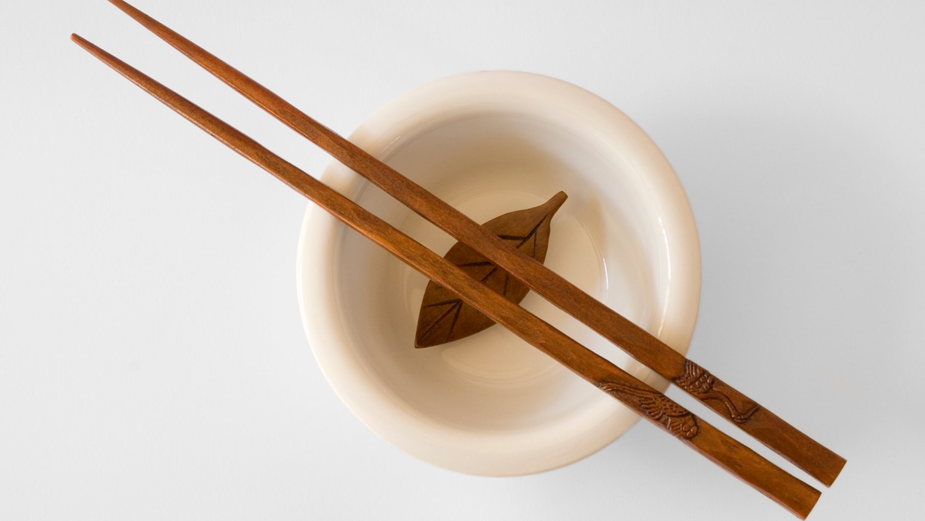 Chopsticks in a bowl with wooden leaf - with clipping path