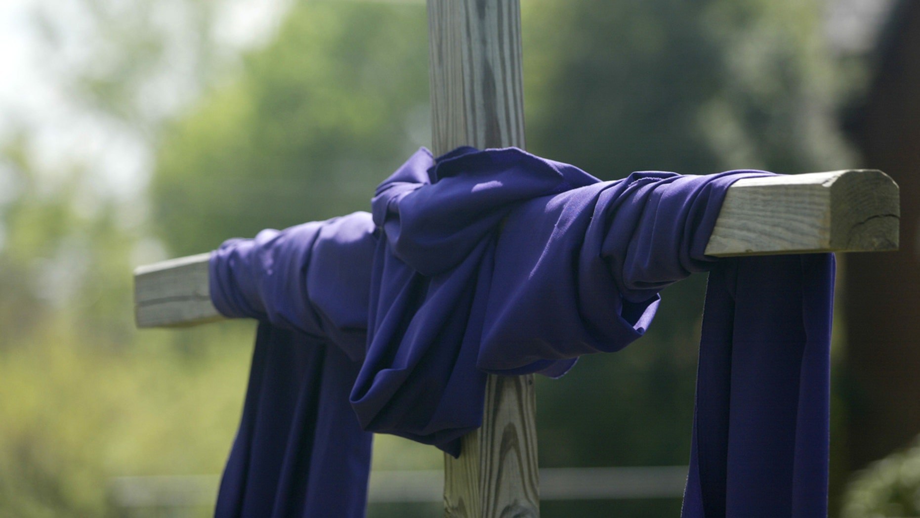 "A wooden cross is wrapped with purple cloth, symbolizing the season of Lent and Easter."