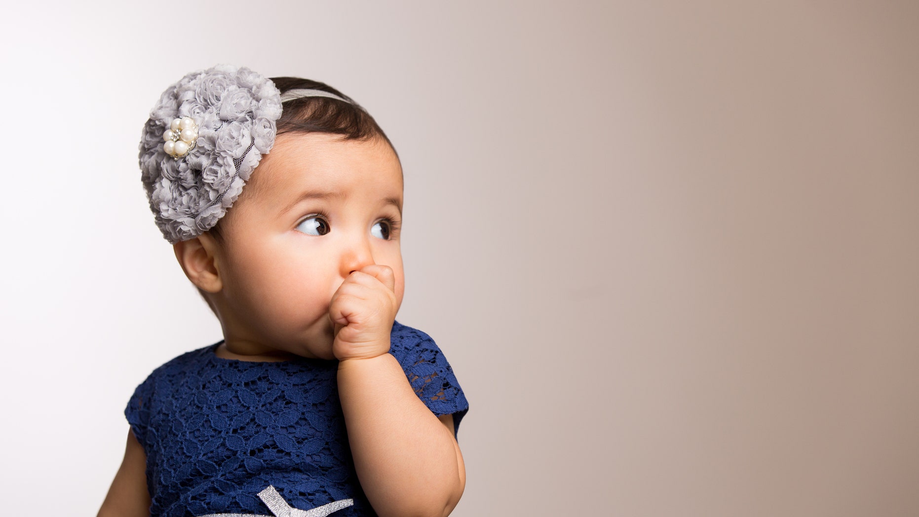 Baby girl sucking her thumb isolated over colored background