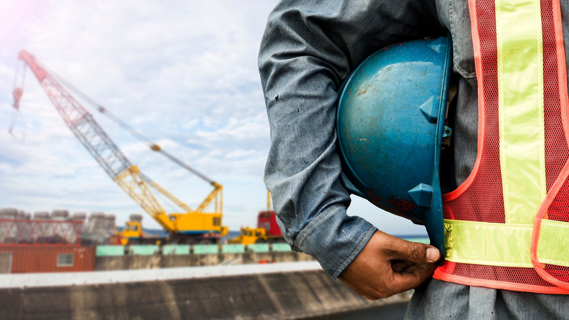 construction worker checking location site with crane on the background