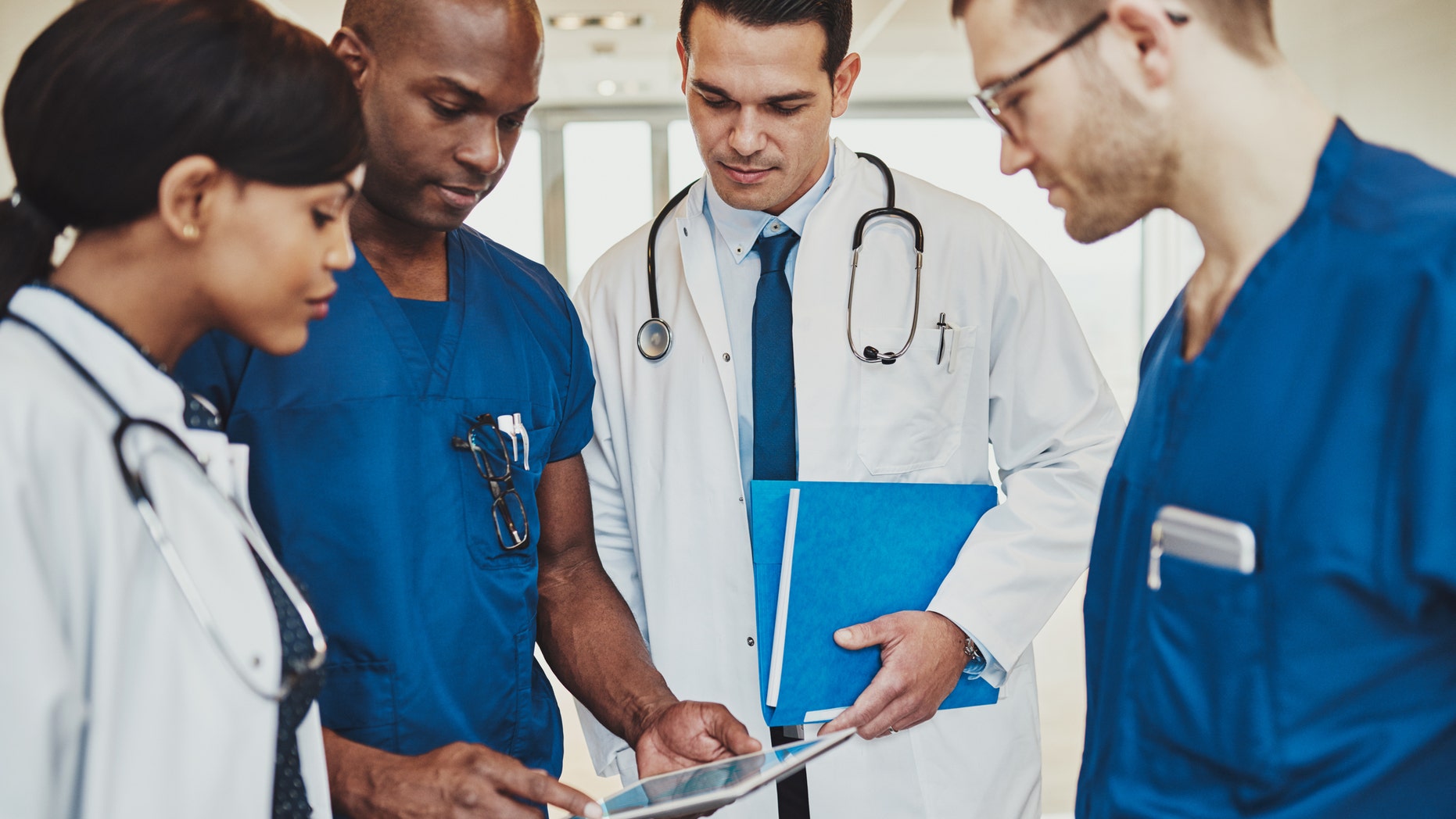 Team of multiracial doctors at hospital discussing a patient, Doctors using tablet