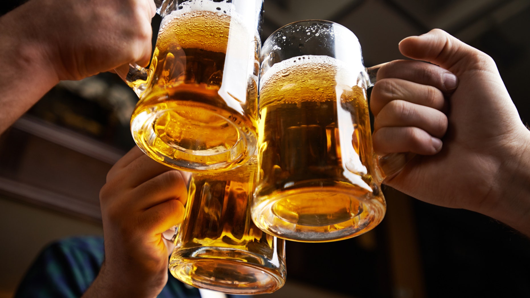 Hands of three men toasting with beer