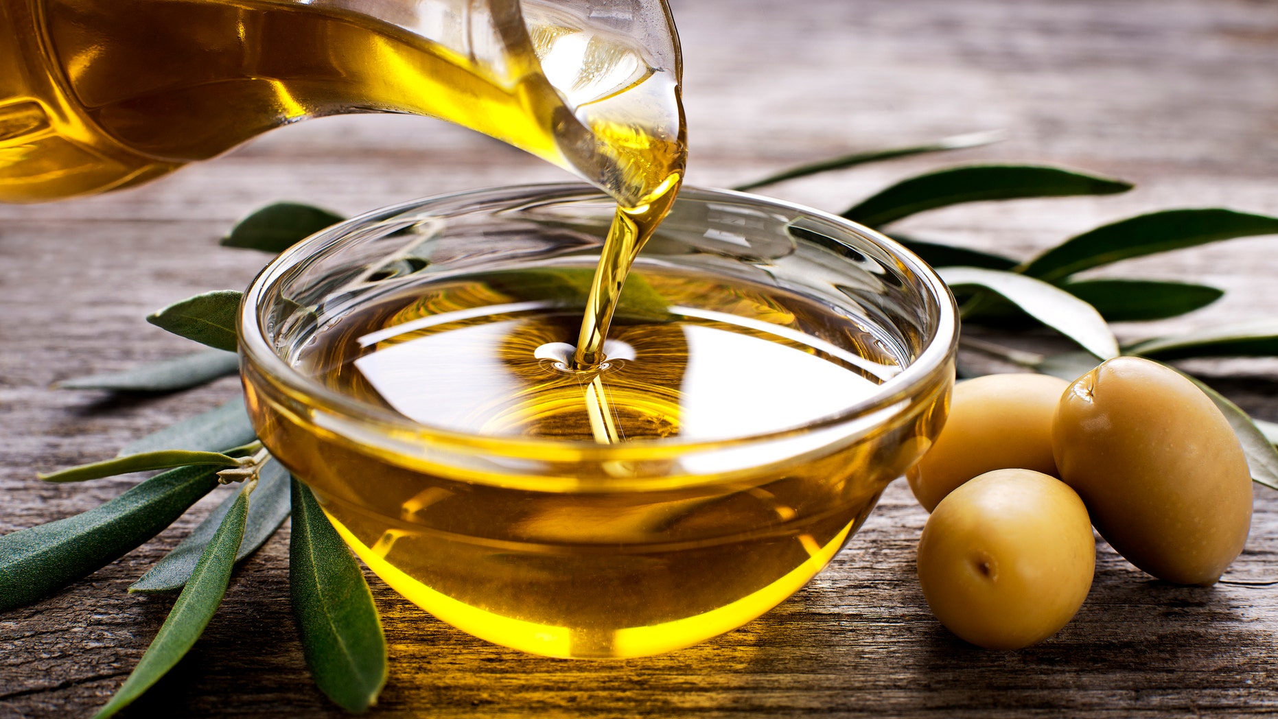 Bottle pouring virgin olive oil in a bowl close up