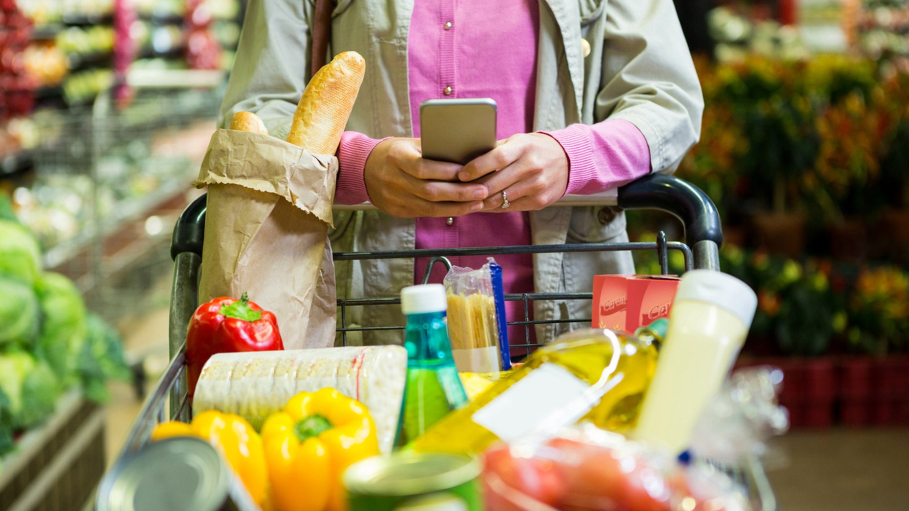 Woman using mobile phone while shopping in supermarket