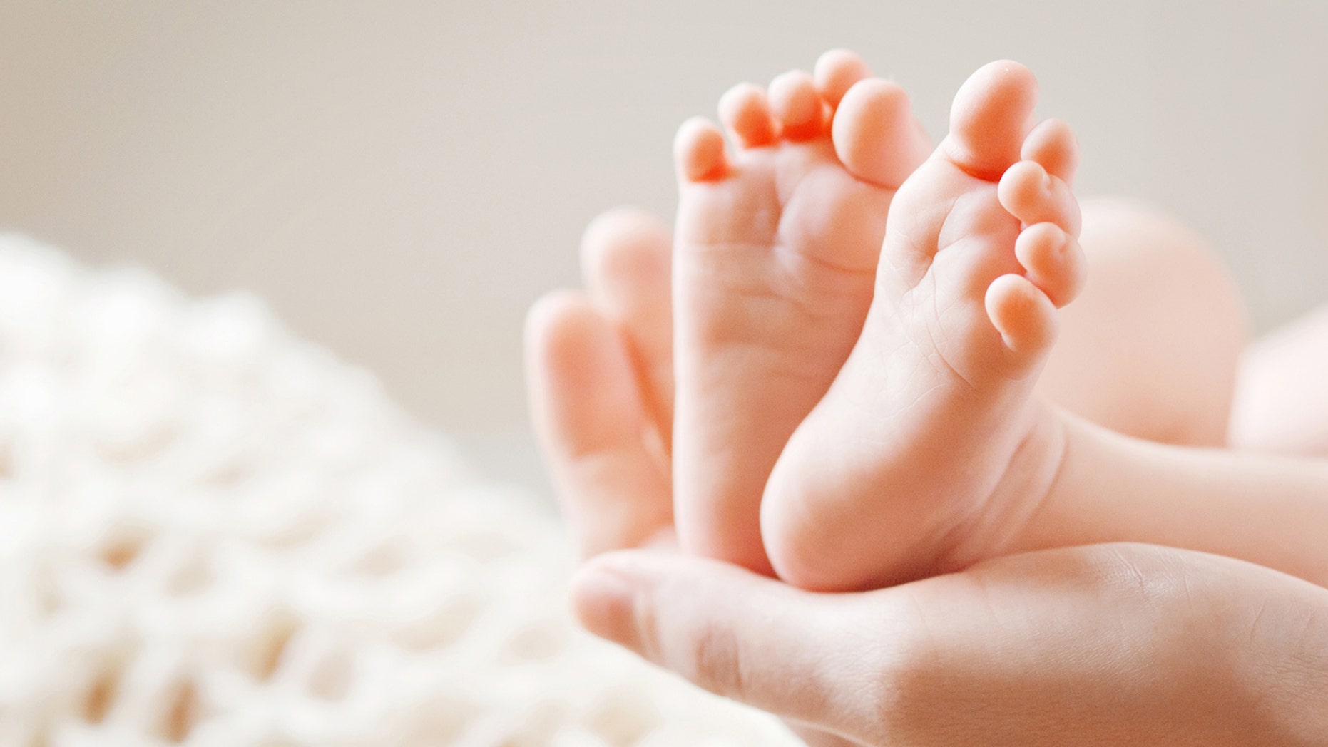 Baby feet in mother hands. Tiny Newborn Baby's feet on female Shaped hands closeup. Mom and her Child. Happy Family concept. Beautiful conceptual image of Maternity
