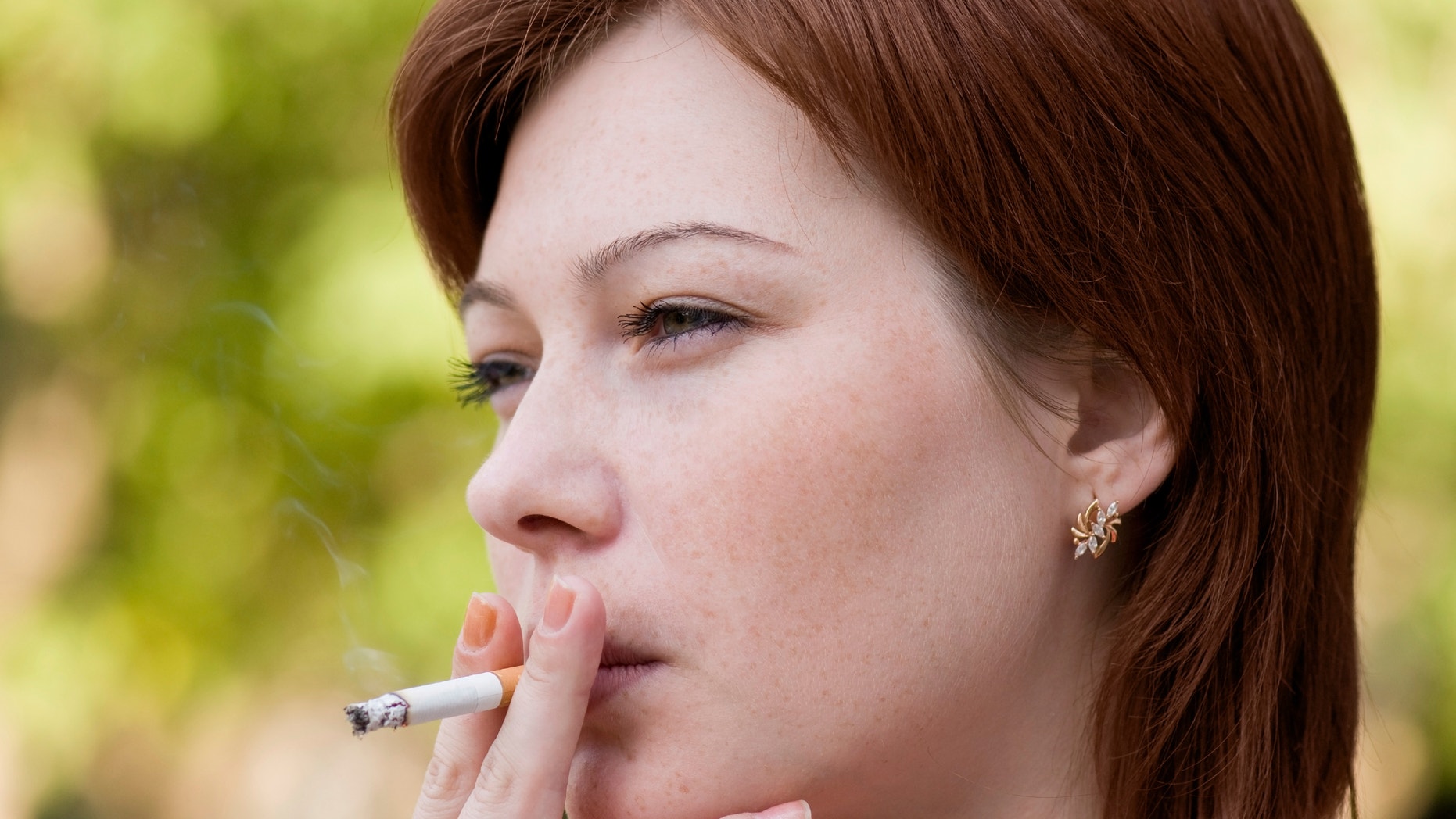 The young woman who is smoking a cigarette and carrying away a smoke in air