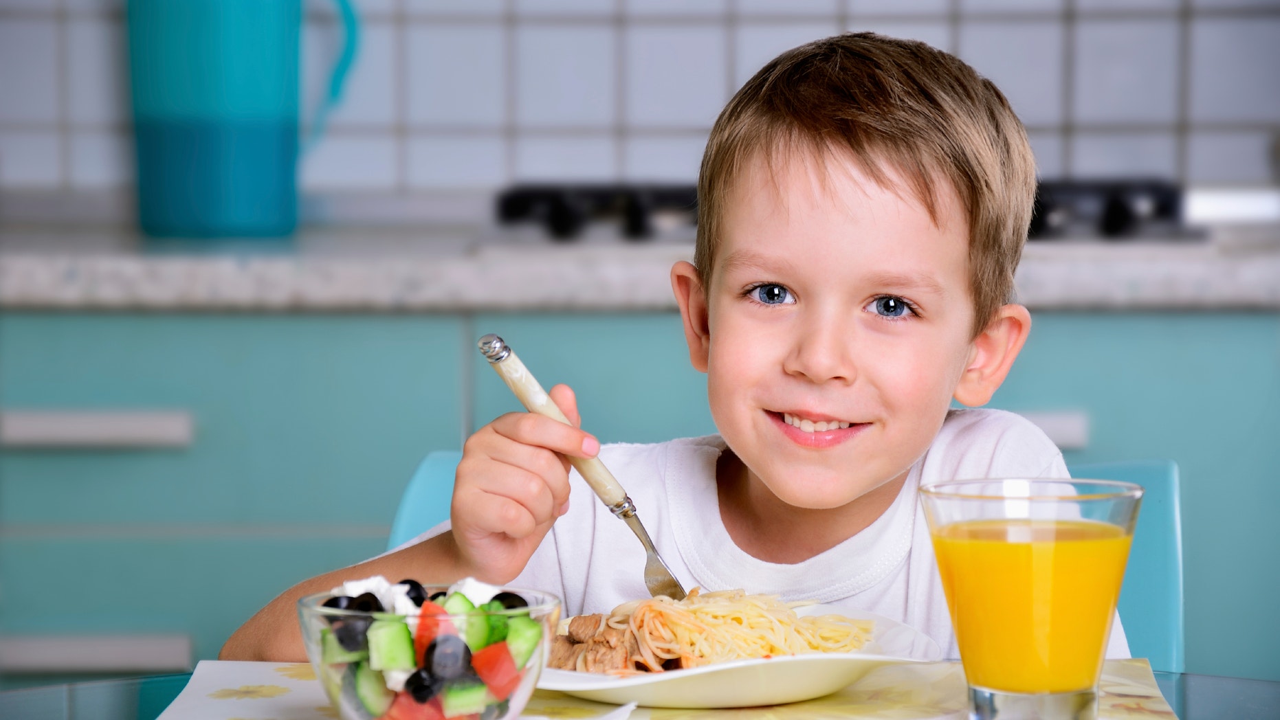 Smiling joyful boy sitting at the dinner table and looking at the camera. horizontal