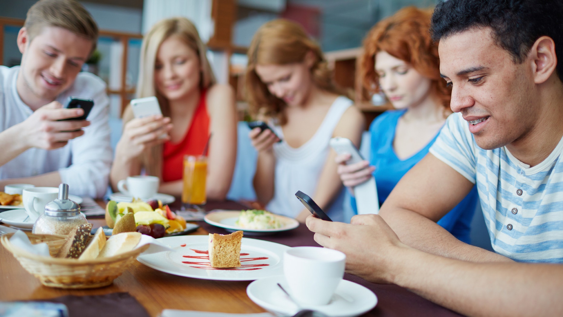 Friends sitting at café absorbed in their phones