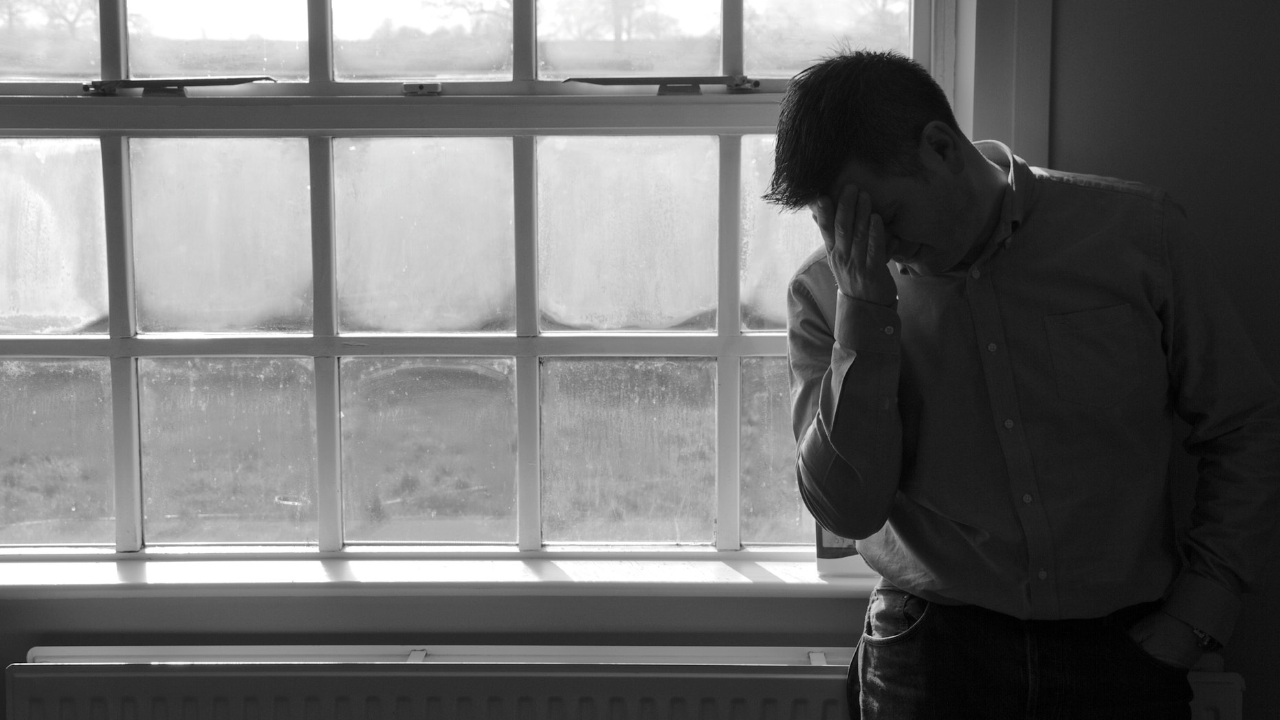 Lone anonymous middle aged man suffering depression or anxiety. Â Looking sad, worried, frustrated, in pain or desperate with hands on head leaning against an empty white wall.