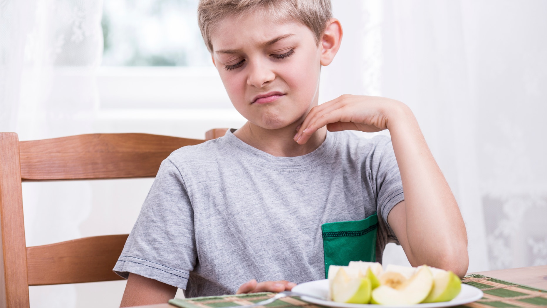 Blonde boy refusing to eat healthy apple