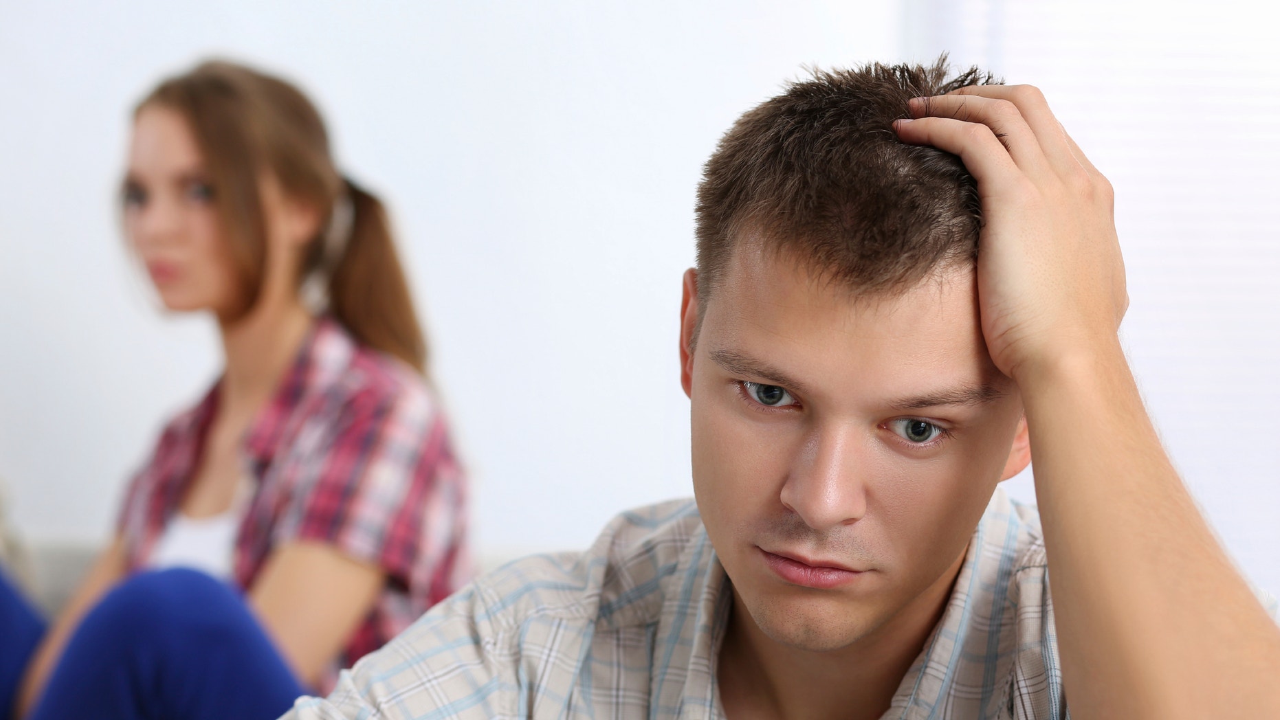 Portrait of unhappy young couple having problems. Focus on man