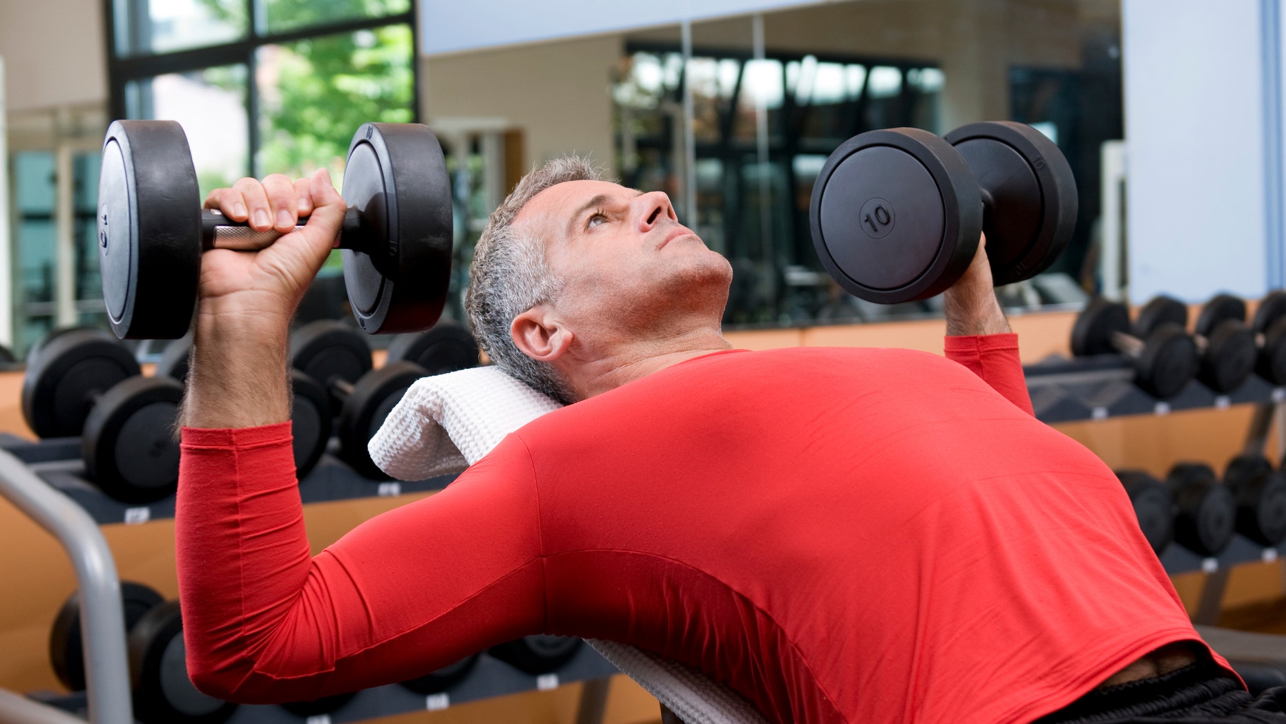Mature man lifting dumbells at fitness gym