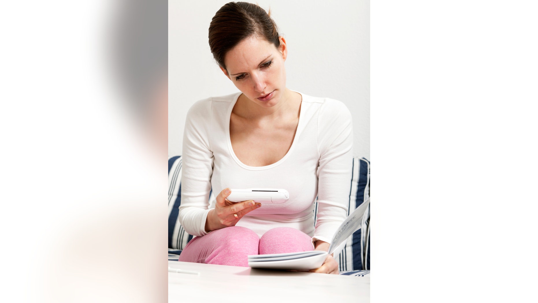 Young woman reading the information booklet that accomanied her ovulation prediction kit in order to determine her most fertile days after release of mature ova