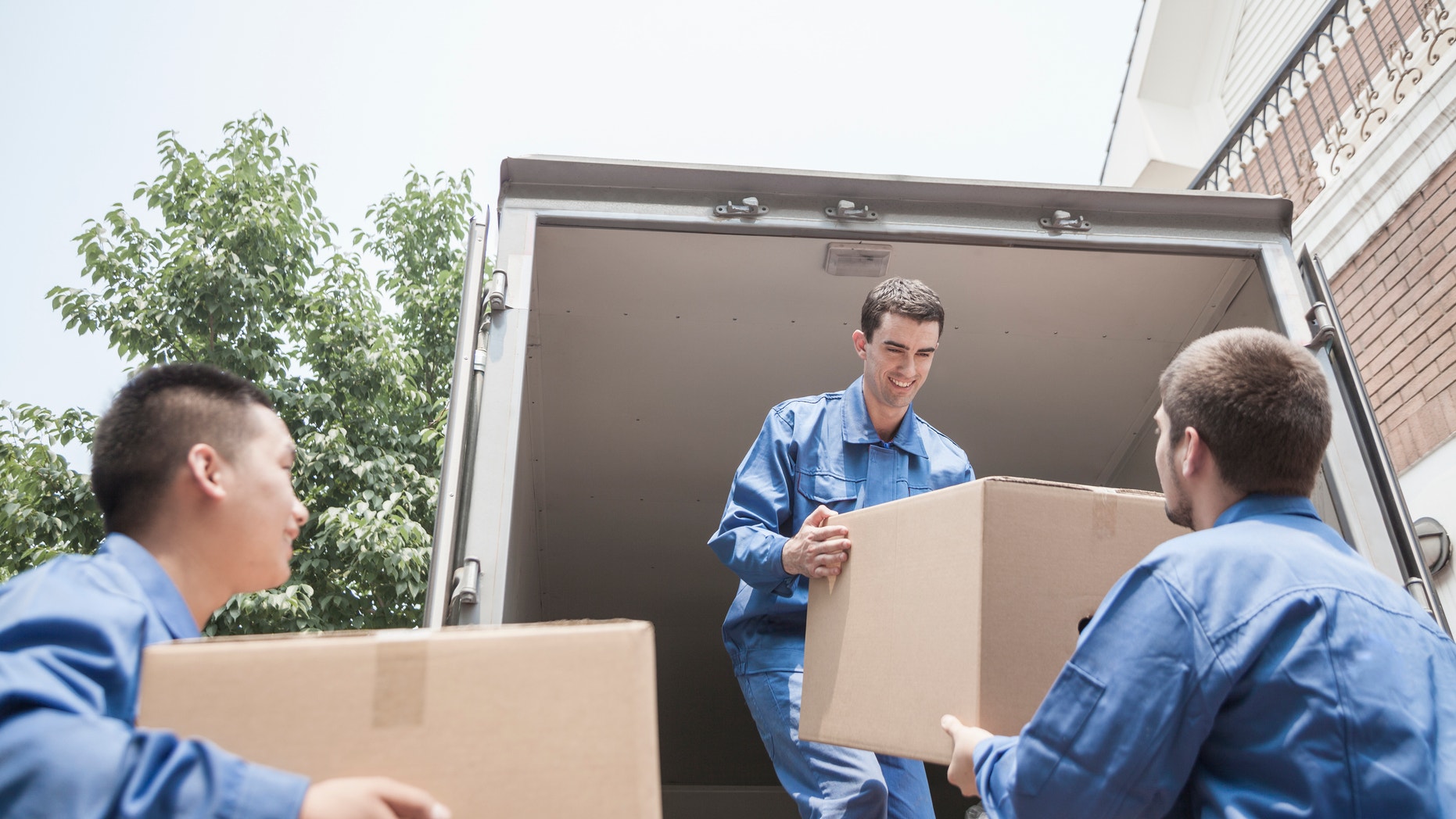 Movers unloading a moving van, passing a cardboard box