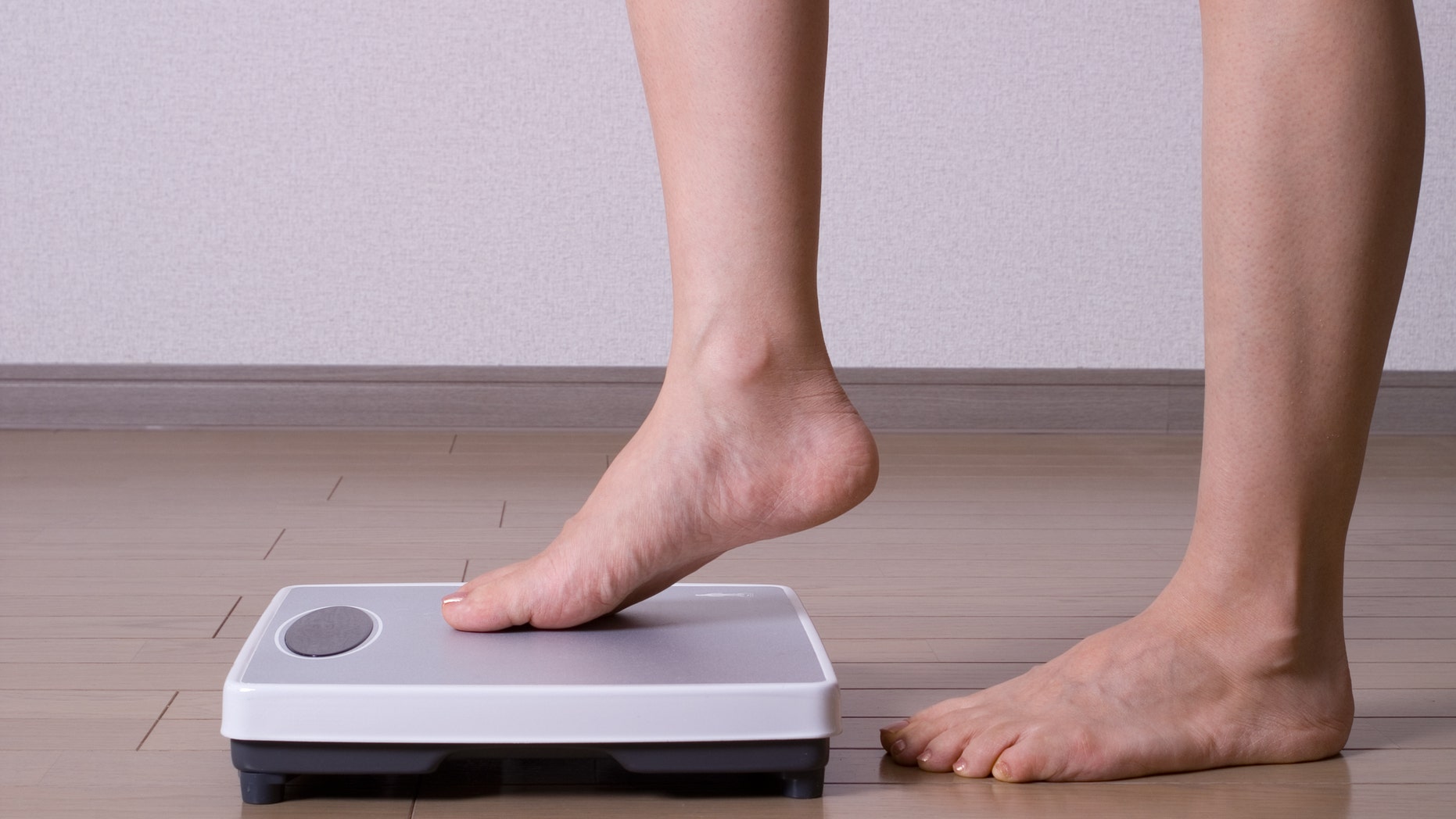 Woman stepping on scales and weighing herself