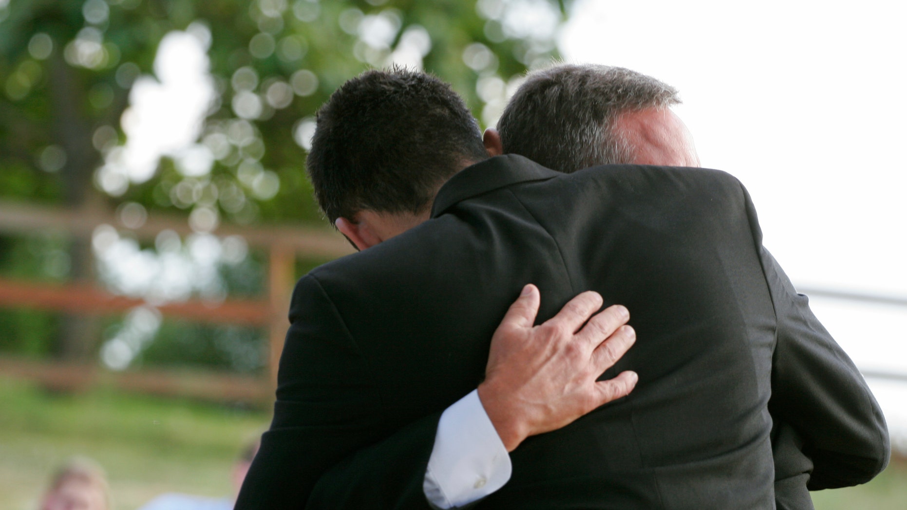 Two men hug each other. Horizontal with copy space.
