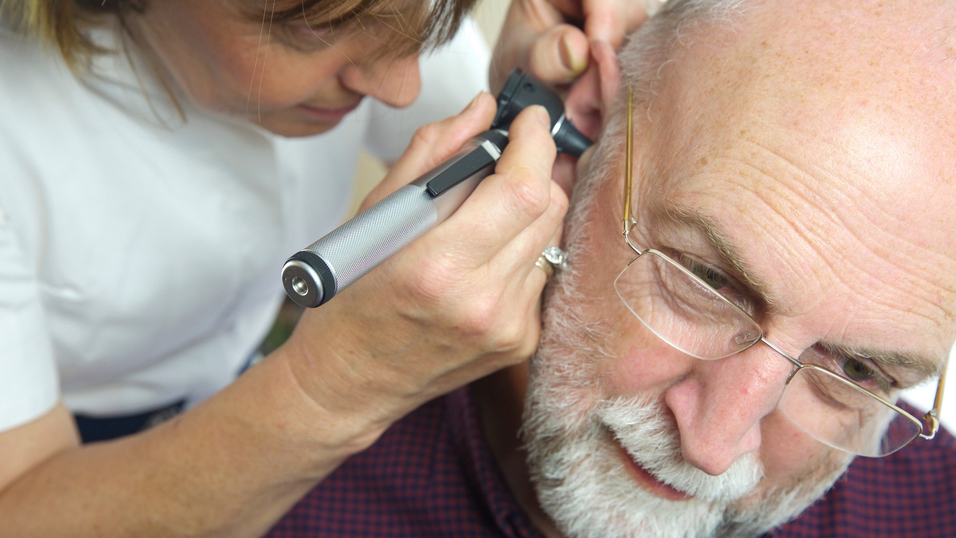 Nurse inspects patient's ear with an auroscope - the ear drum is evident from the image - all clear!