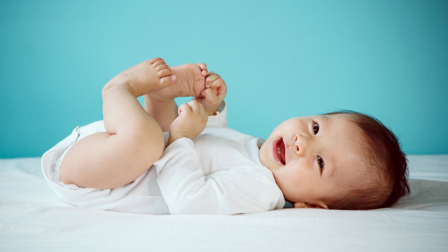 Portrait of a cute 7 months baby lying down on a bed, new family and love concept.
