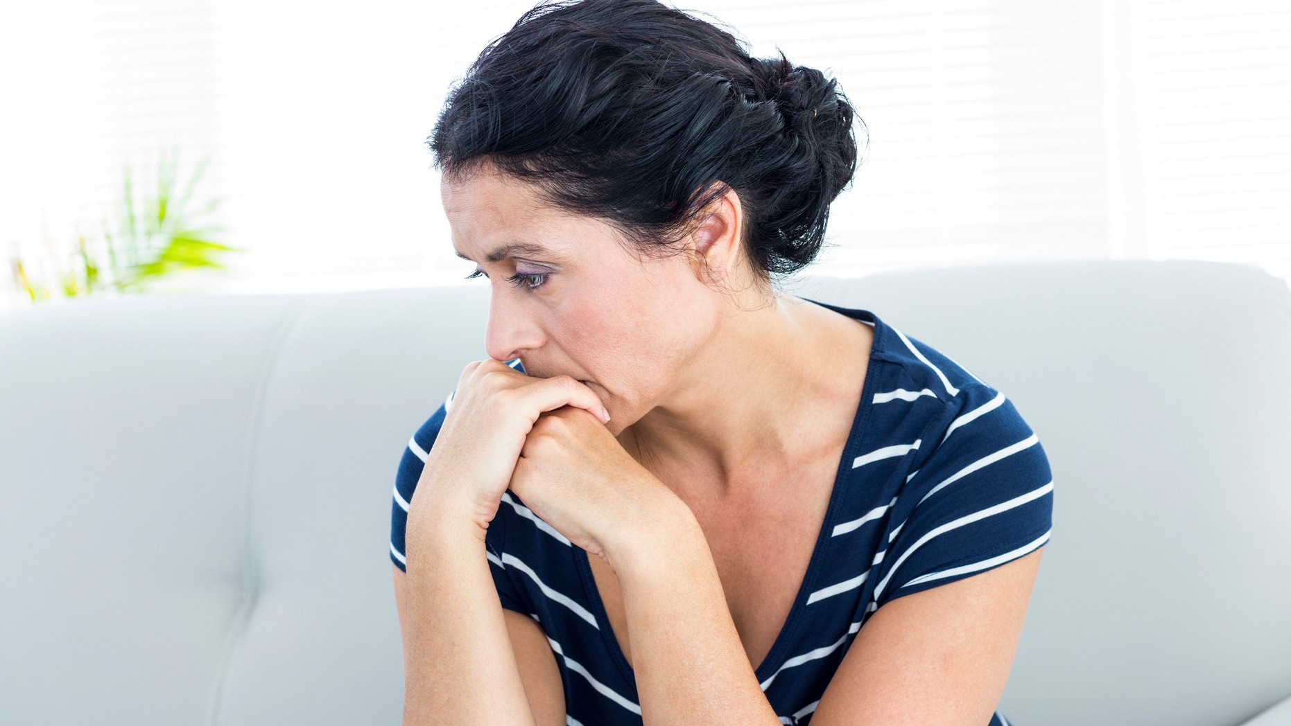 Unhappy woman sitting on the couch on white background