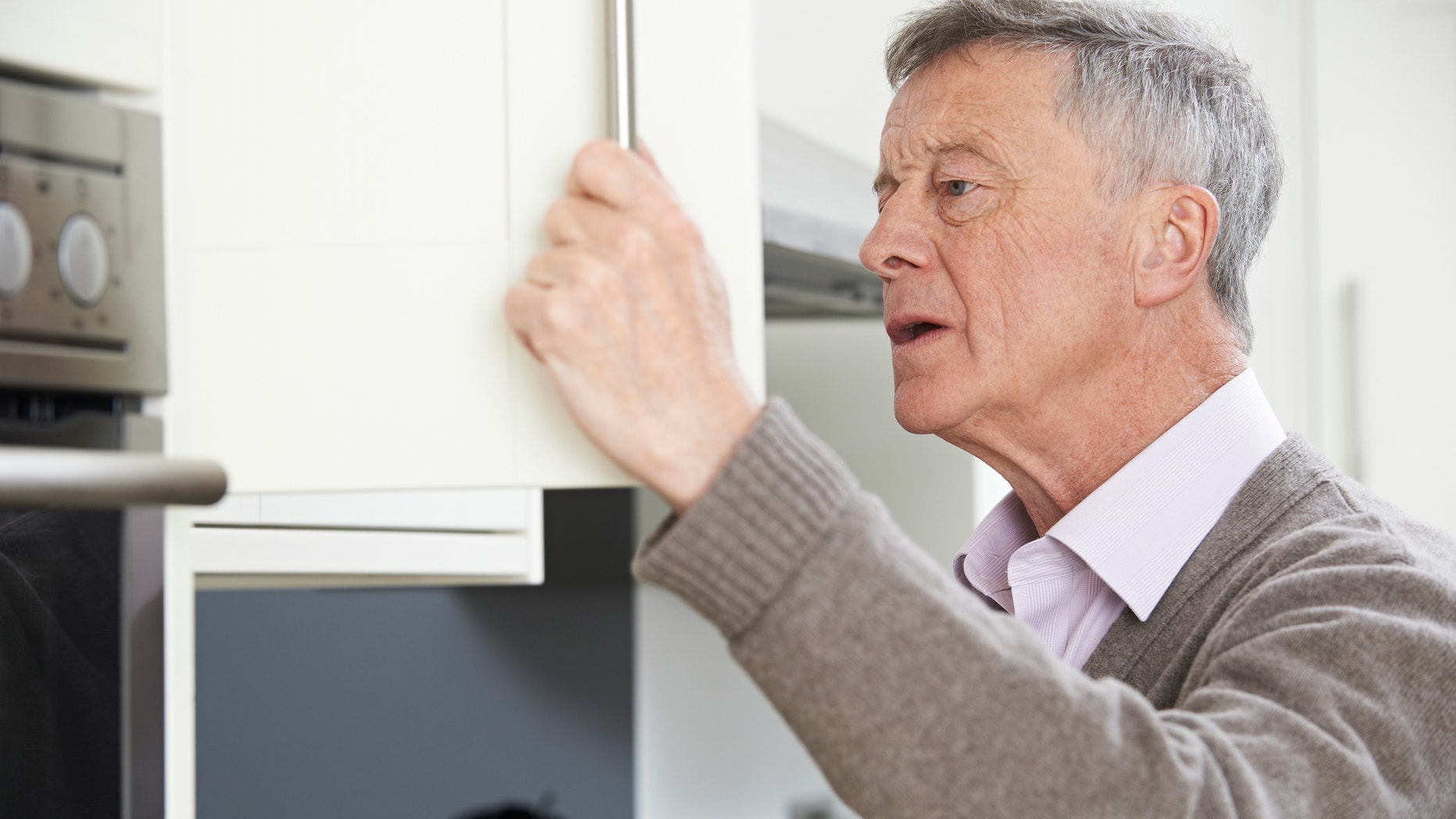 Forgetful Senior Man Looking In Cupboard