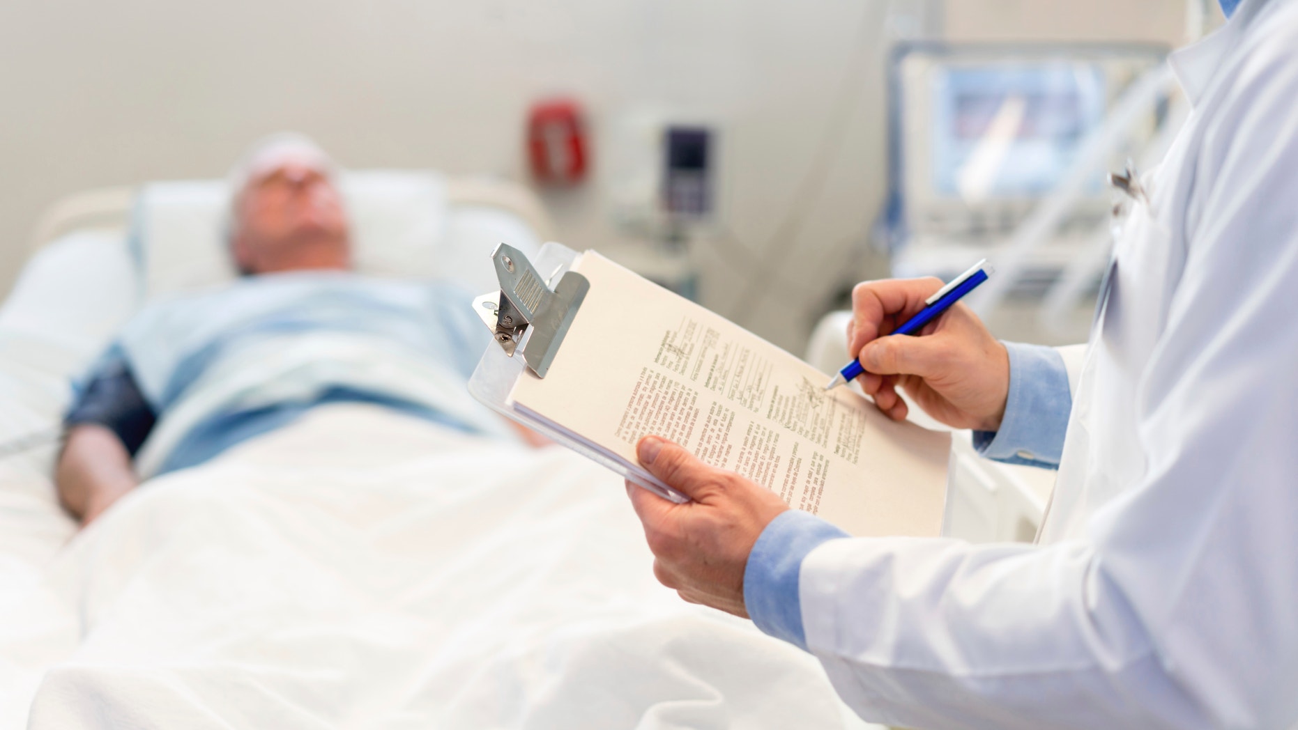 Doctor checking on a senior patient at the ER close-up on a clipboard