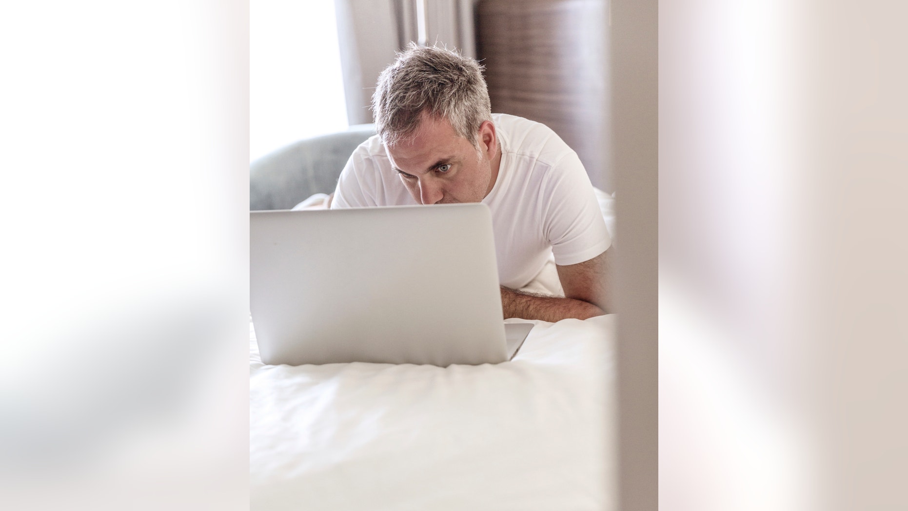 Man Using Laptop in Bed