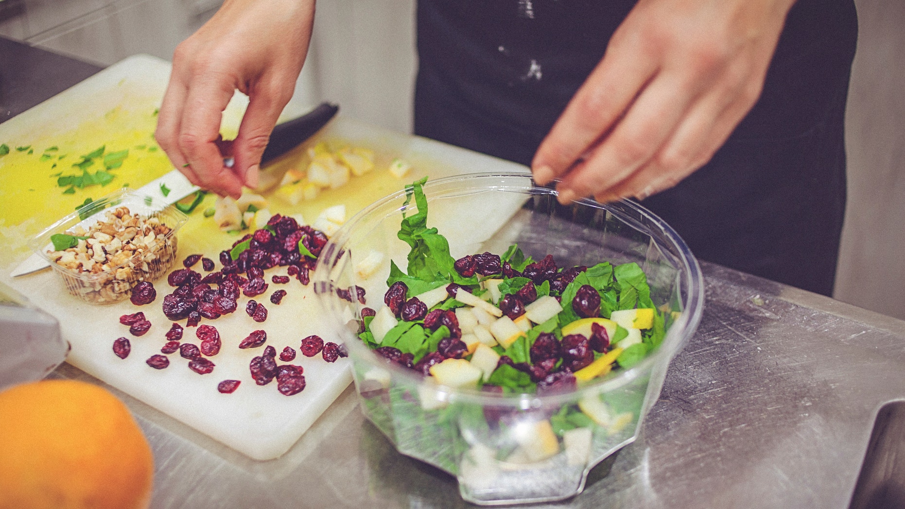 Close-up of a female hands cutting fruits and vegetables and preparing organic salad.