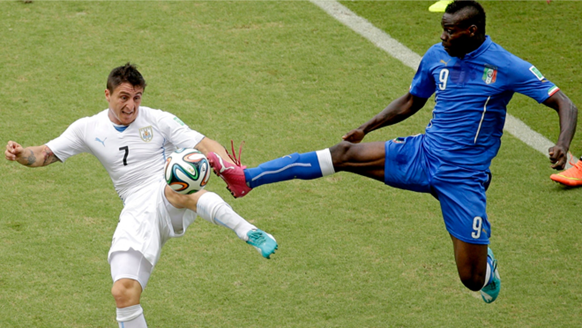 June 24, 2014: Italy's Mario Balotelli (9) and Uruguay's Cristian Rodriguez (7) battle for the ball during the group D World Cup soccer match between Italy and Uruguay at the Arena das Dunas in Natal, Brazil.