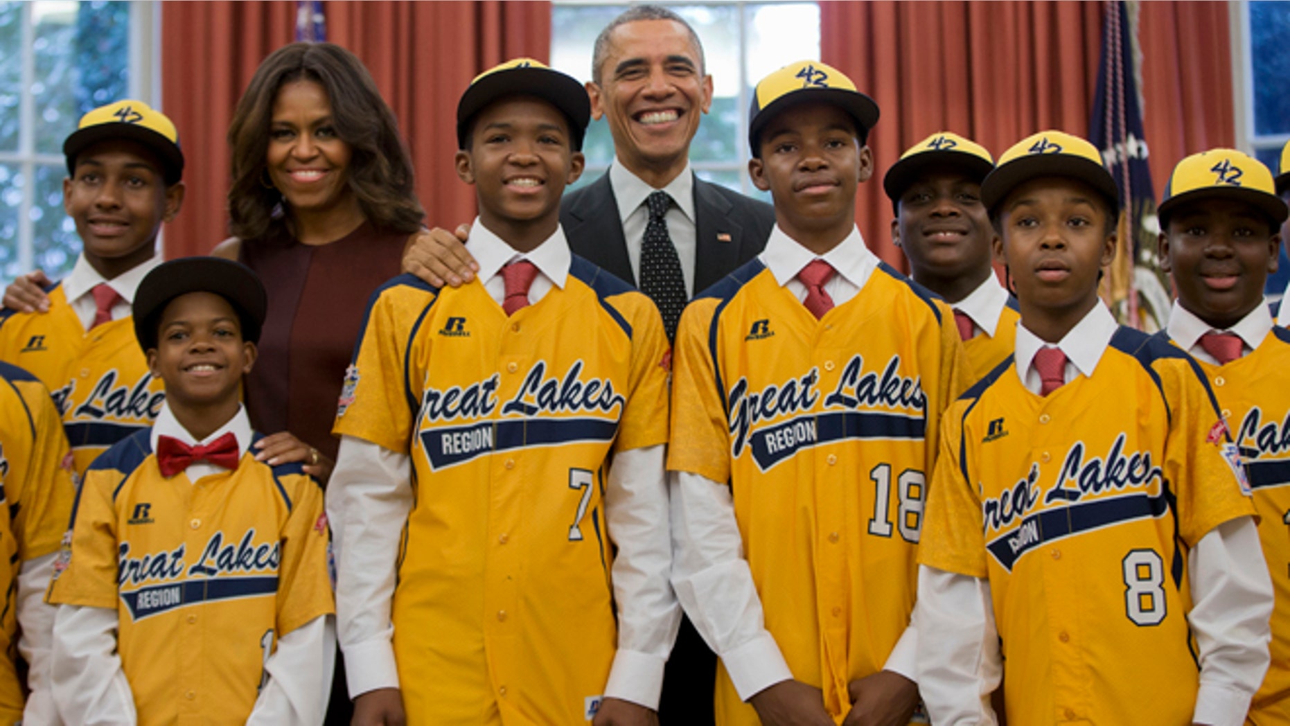 In this Nov. 6, 2014, file photo President Barack Obama and first lady Michelle Obama pose with members of the Jackie Robinson West little league team in the Oval Office of the White House in Washington. Little League International has stripped Chicago's Jackie Robinson West team of its national title after finding the team falsified its boundary map.