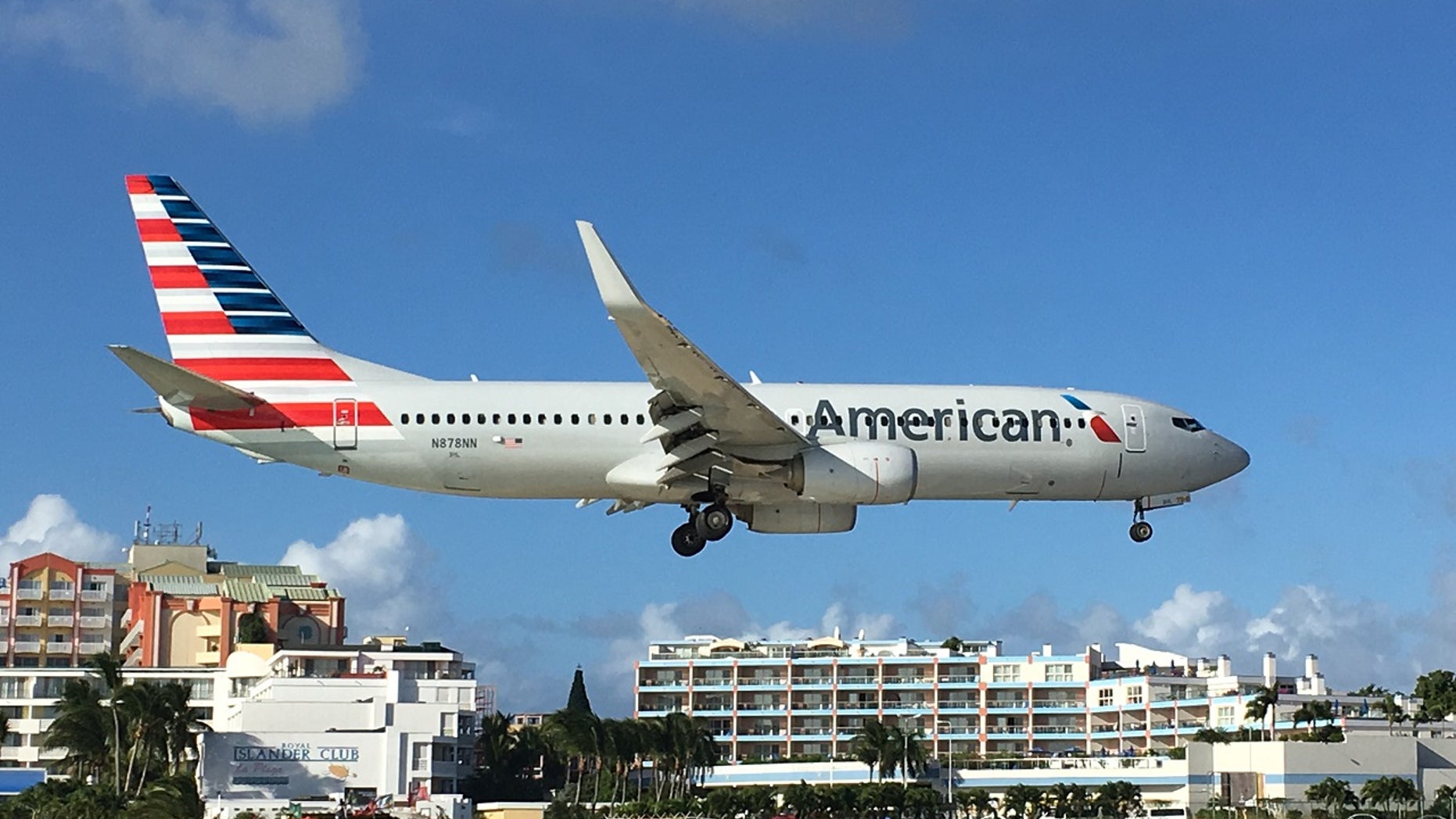 An American Airlines plane zooms over beachgoers.