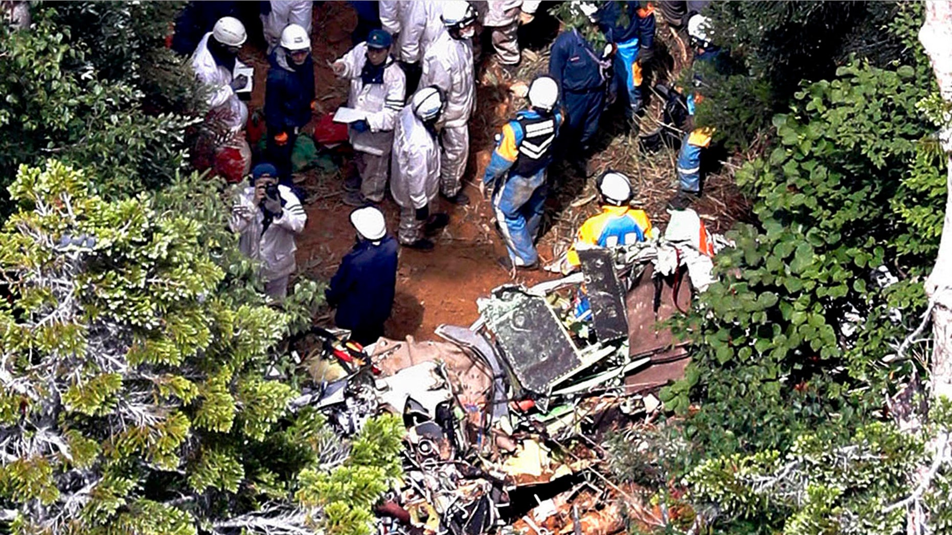 Investigators work near the wreckage of a Japanese search and rescue helicopter that crashed into the central mountains in Nakanojo, Gunma prefecture, northwest of Tokyo, Aug. 11, 2018.