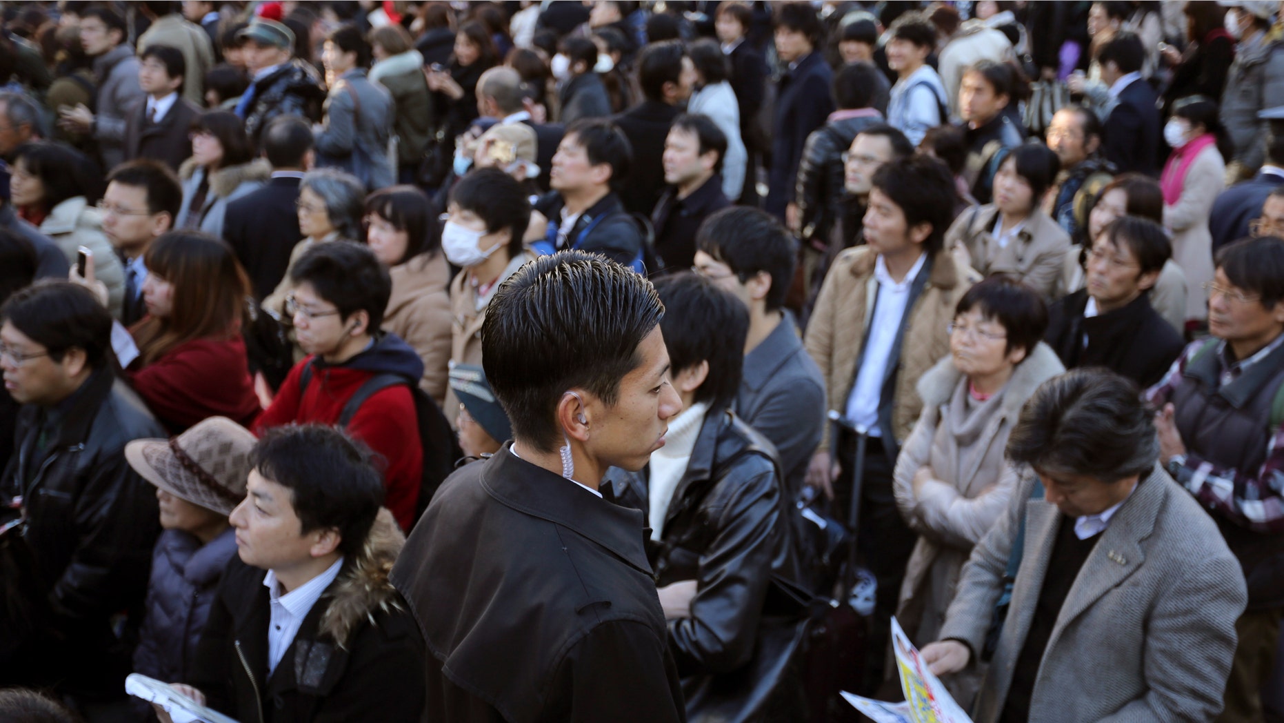 Dec. 13, 2014: A plainclothes police officer, center, stands guard as supporters and passersby listen to a speech by Banri Kaieda